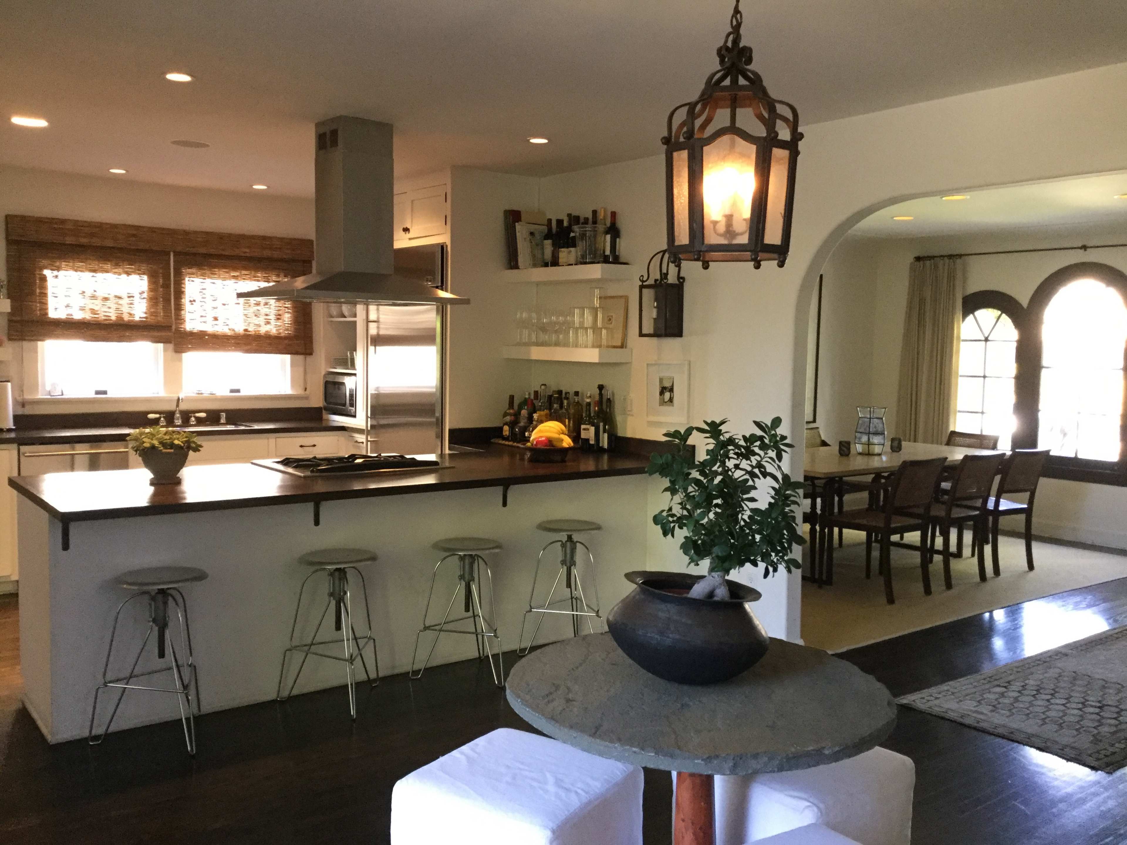 A modern kitchen with a central island featuring bar stools, and a dining area that is partially visible in the background.