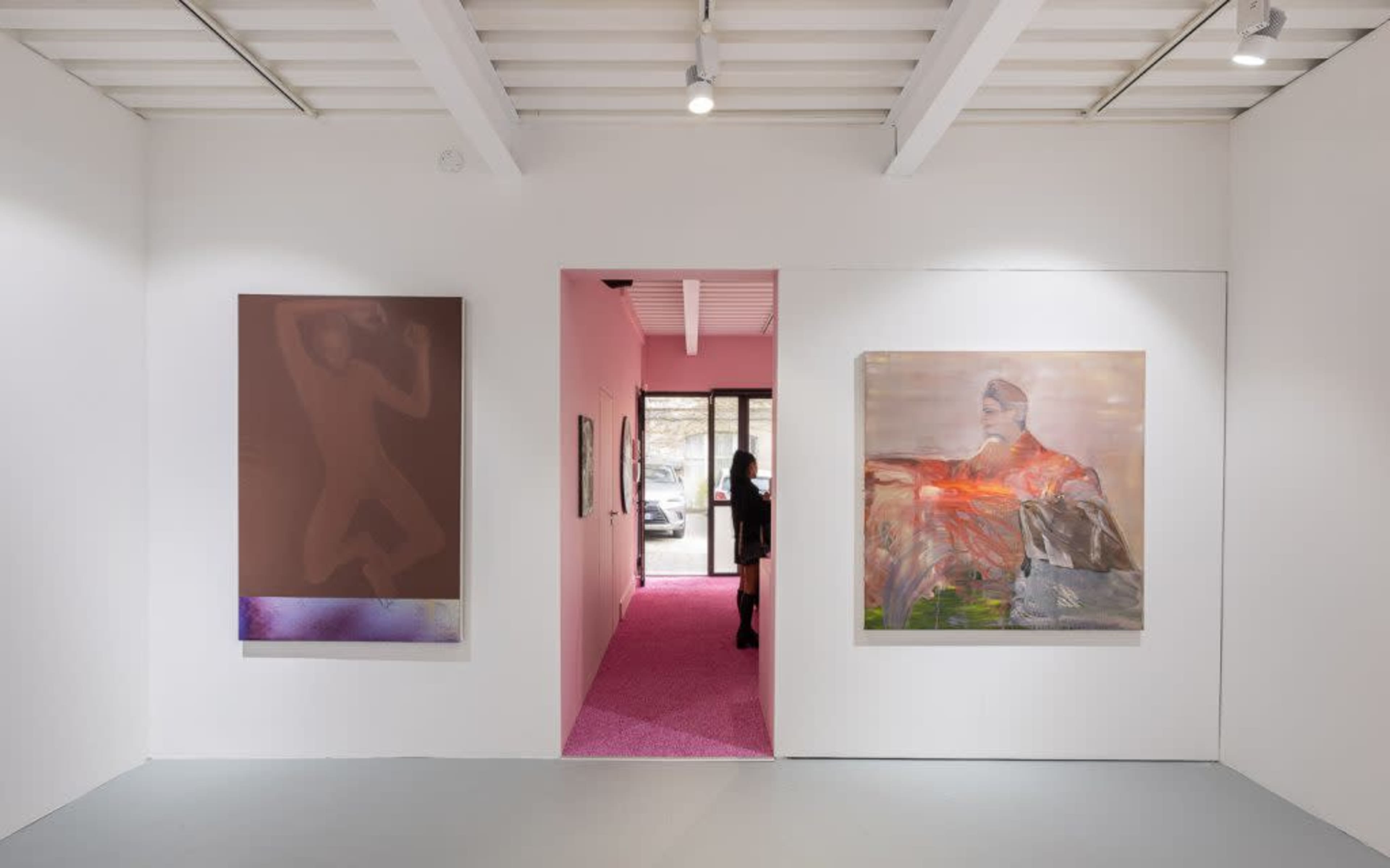 An art gallery with two paintings on the white walls and a doorway leading to a pink-carpeted area.