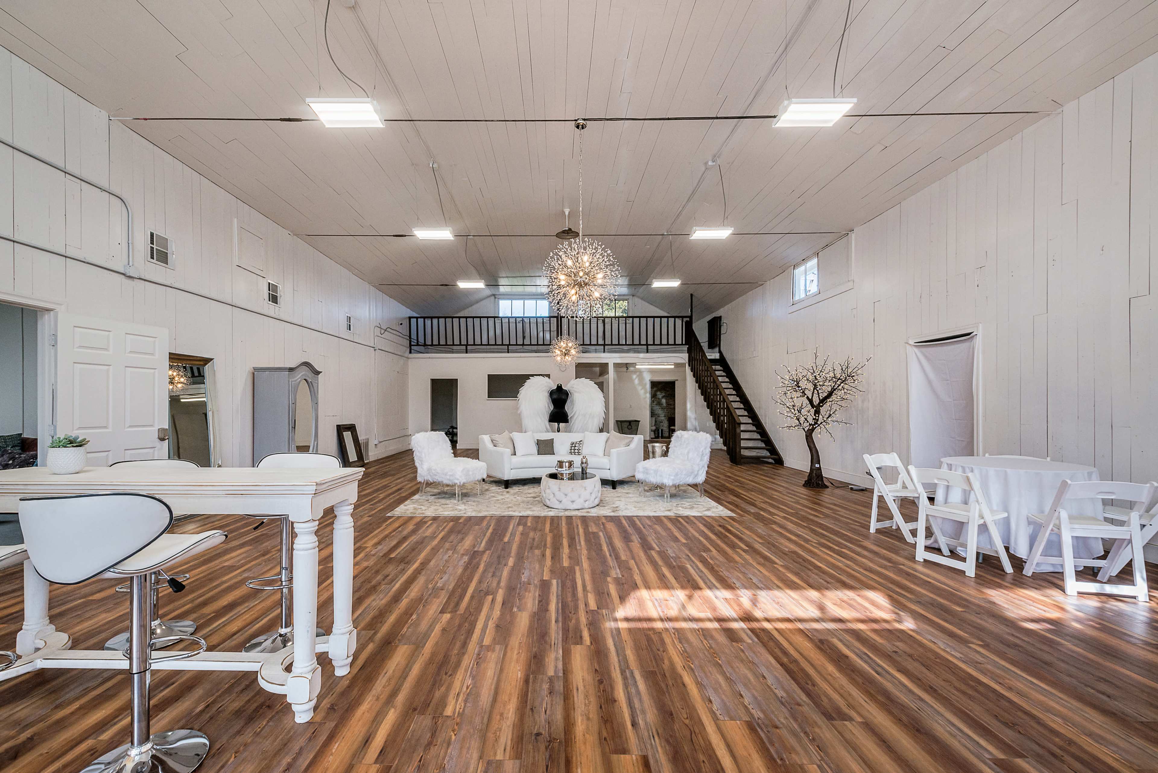 A spacious, well-lit interior featuring modern furniture, elegant lighting, and hardwood flooring.