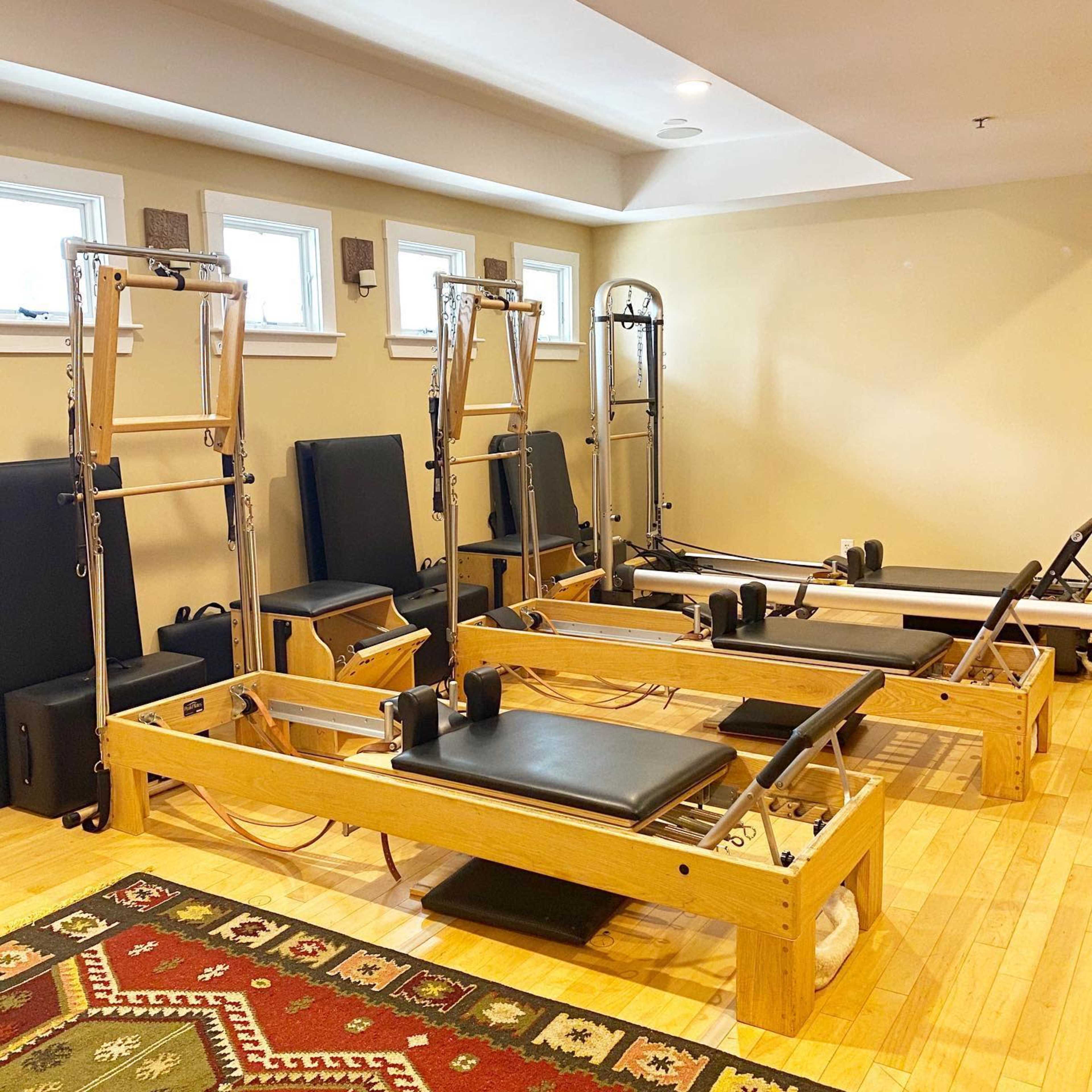 A Pilates studio equipped with several reformer machines arranged neatly on a wooden floor.