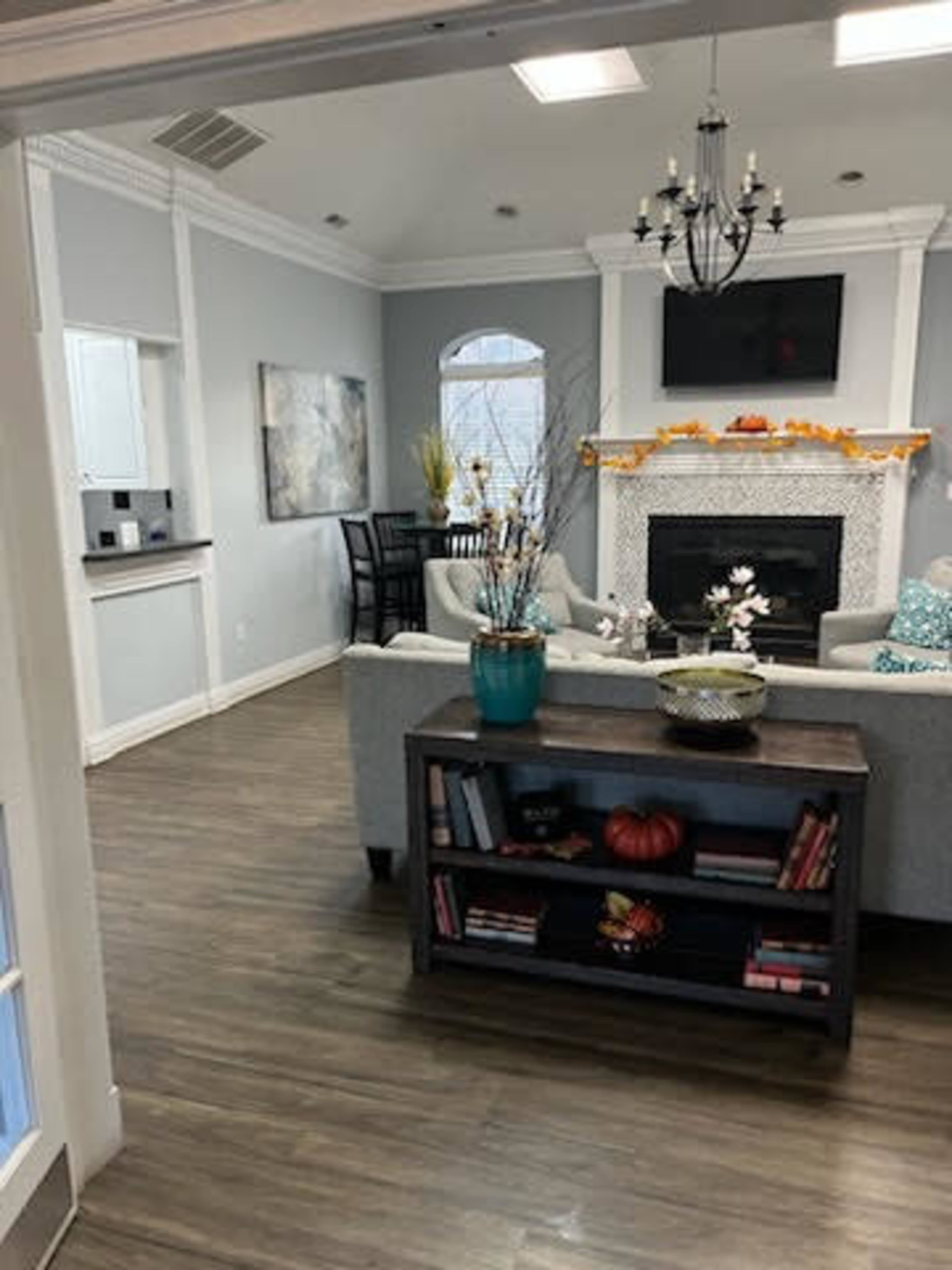 A living room with a gray sofa, a fireplace adorned with decorations, and a view of a dining area through an open doorway.