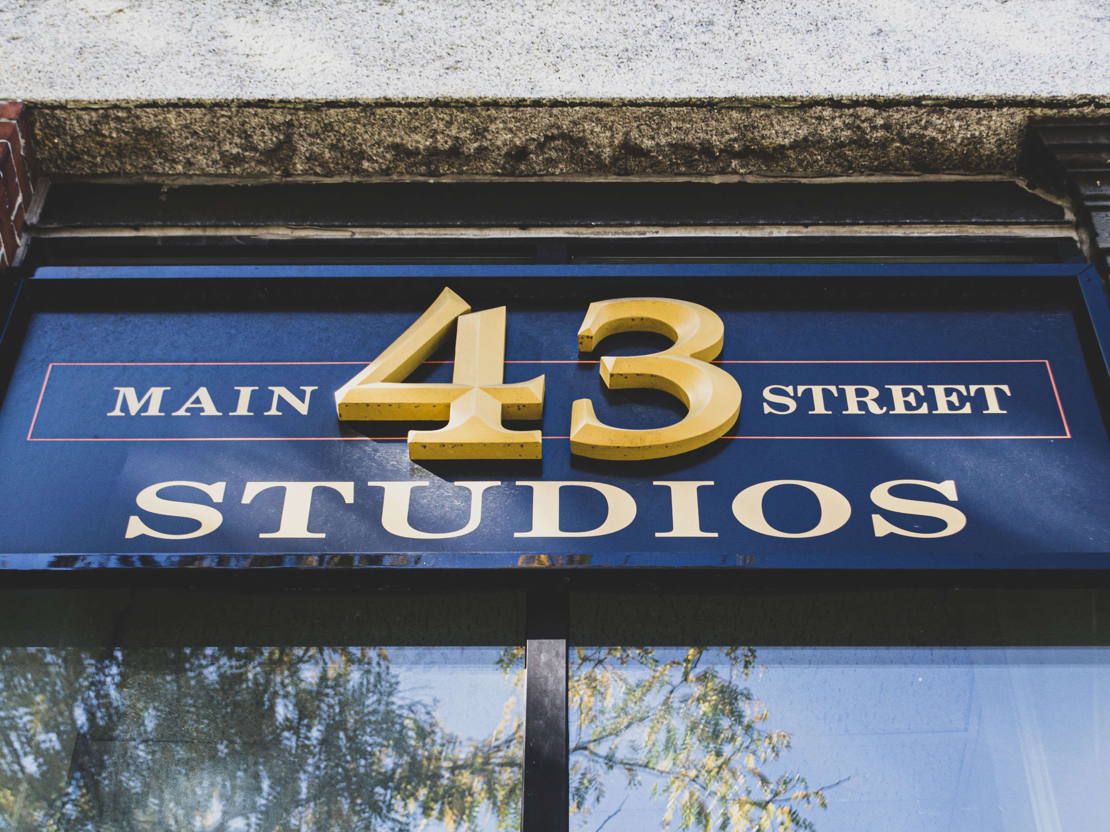 The image features a sign reading "MAIN 43 STREET STUDIOS" in gold and white lettering on a dark blue background.
