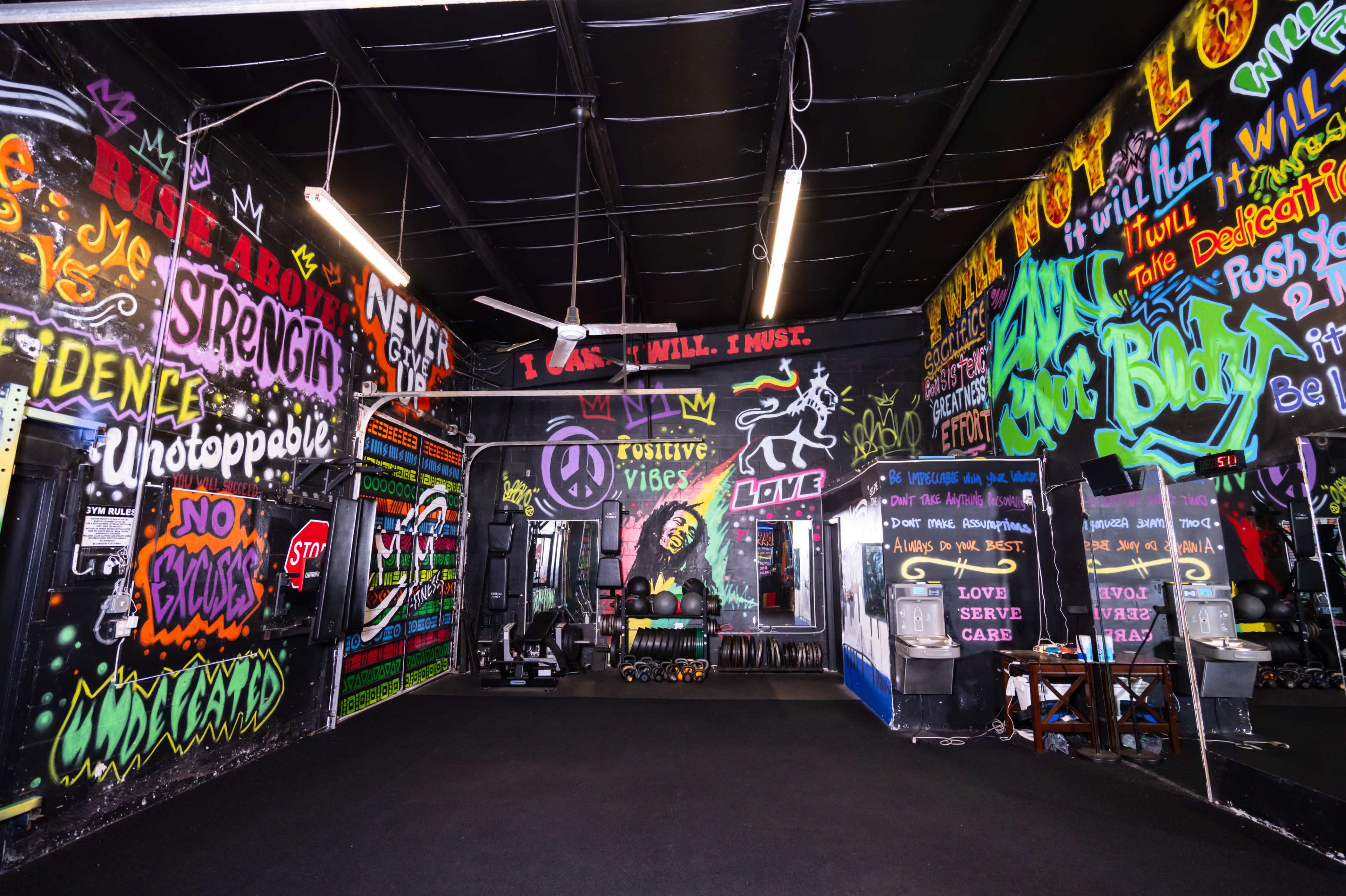 A vibrant gym interior adorned with colorful graffiti and motivational phrases on the walls.