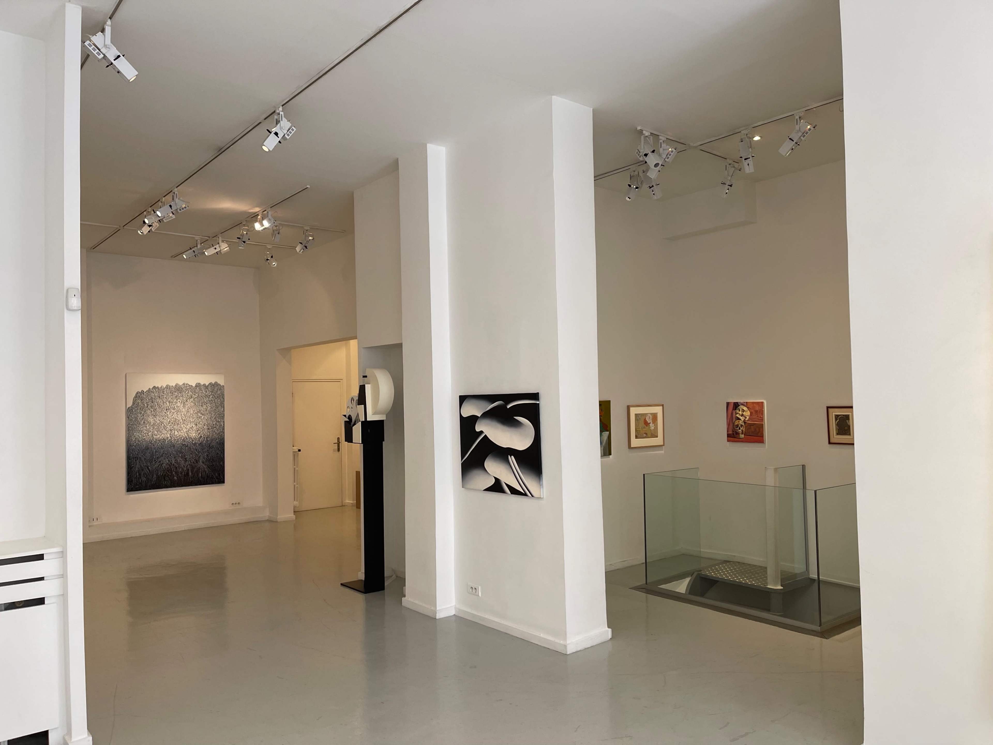 An art gallery with white walls and various artworks displayed, including paintings and a sculpture.