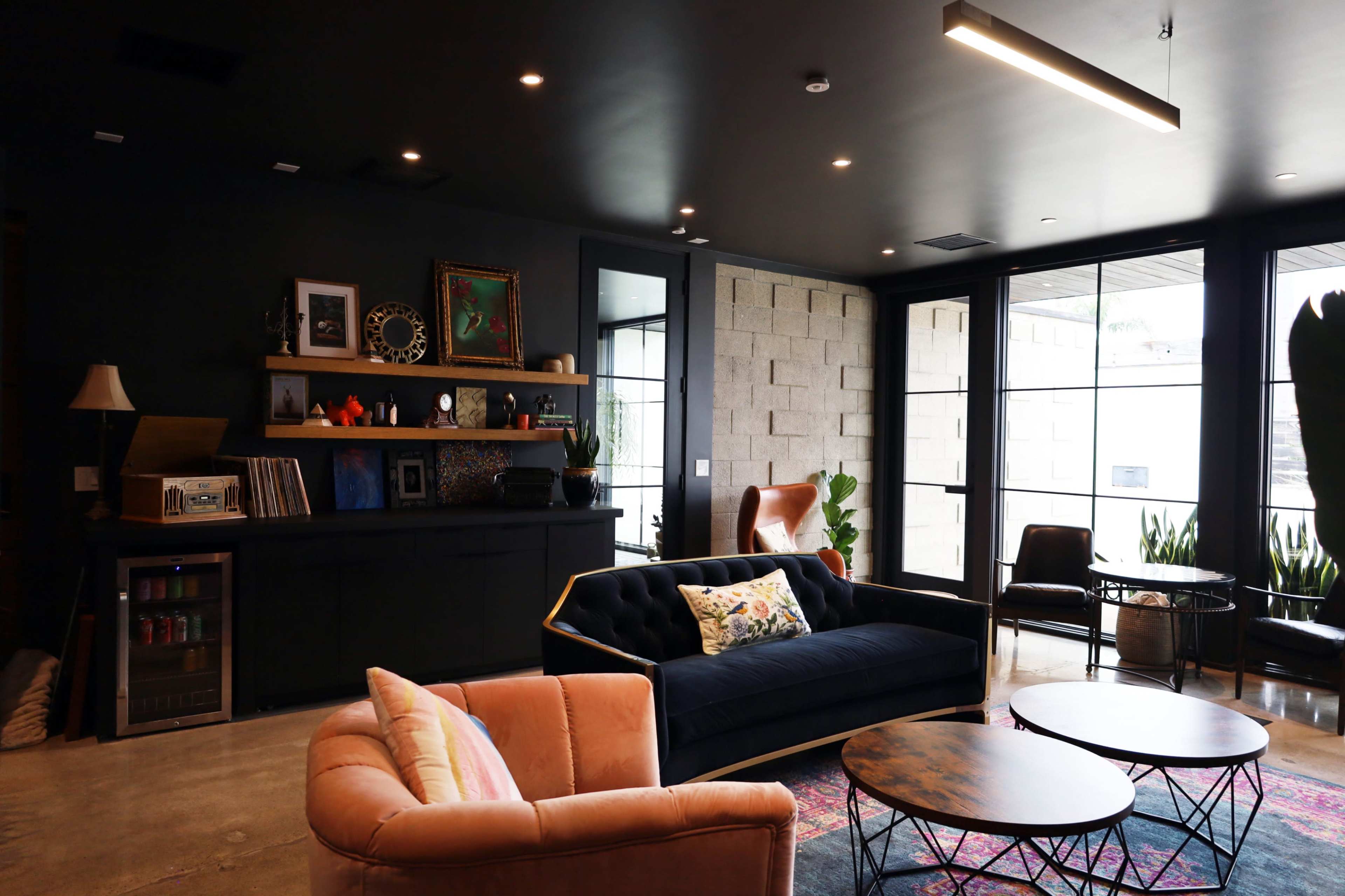 The image shows a stylish lounge area featuring two sofas, a coffee table, and large windows that allow natural light to enter the space.