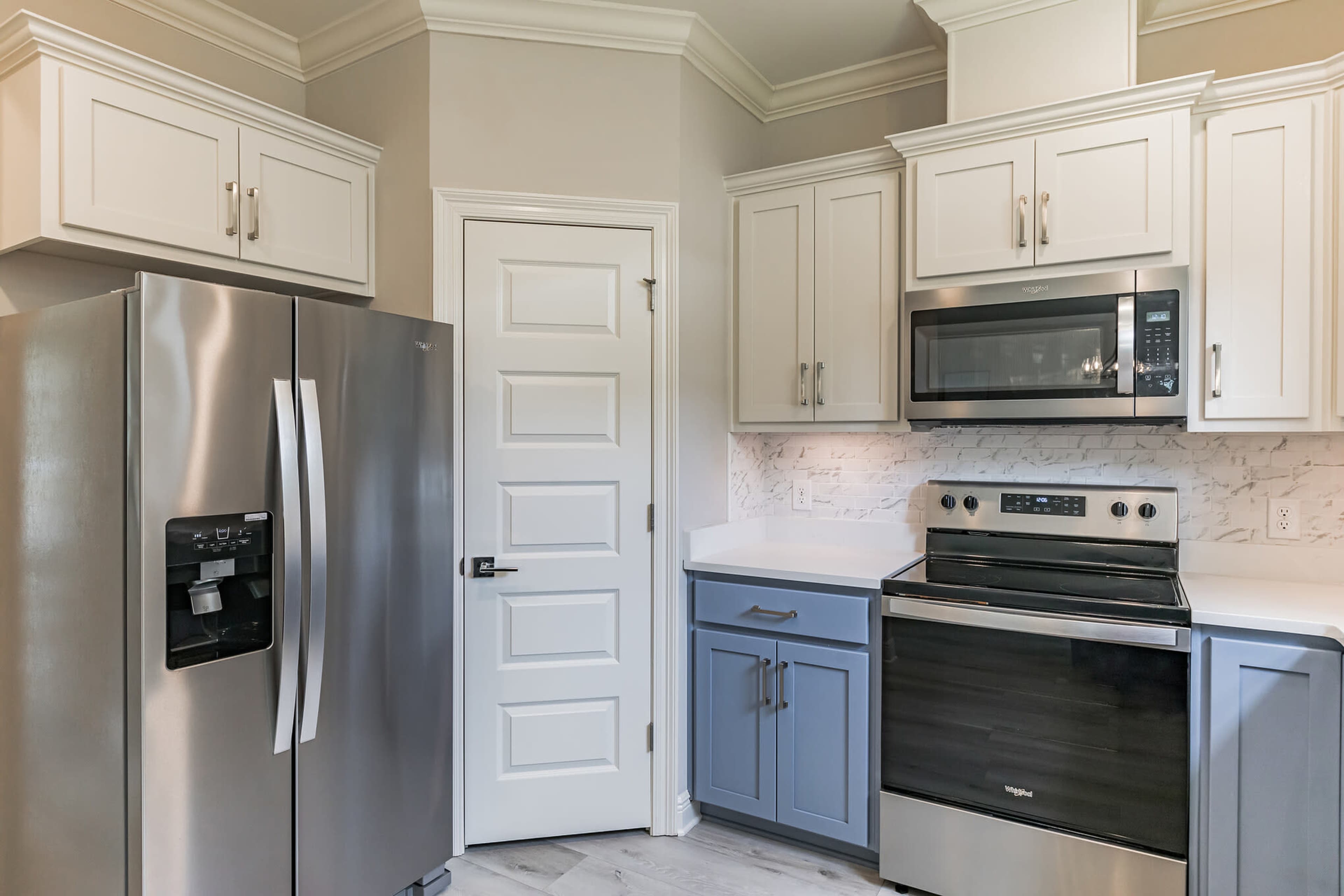 A modern kitchen featuring stainless steel appliances, white cabinetry, and a blue accent on the lower cabinets.