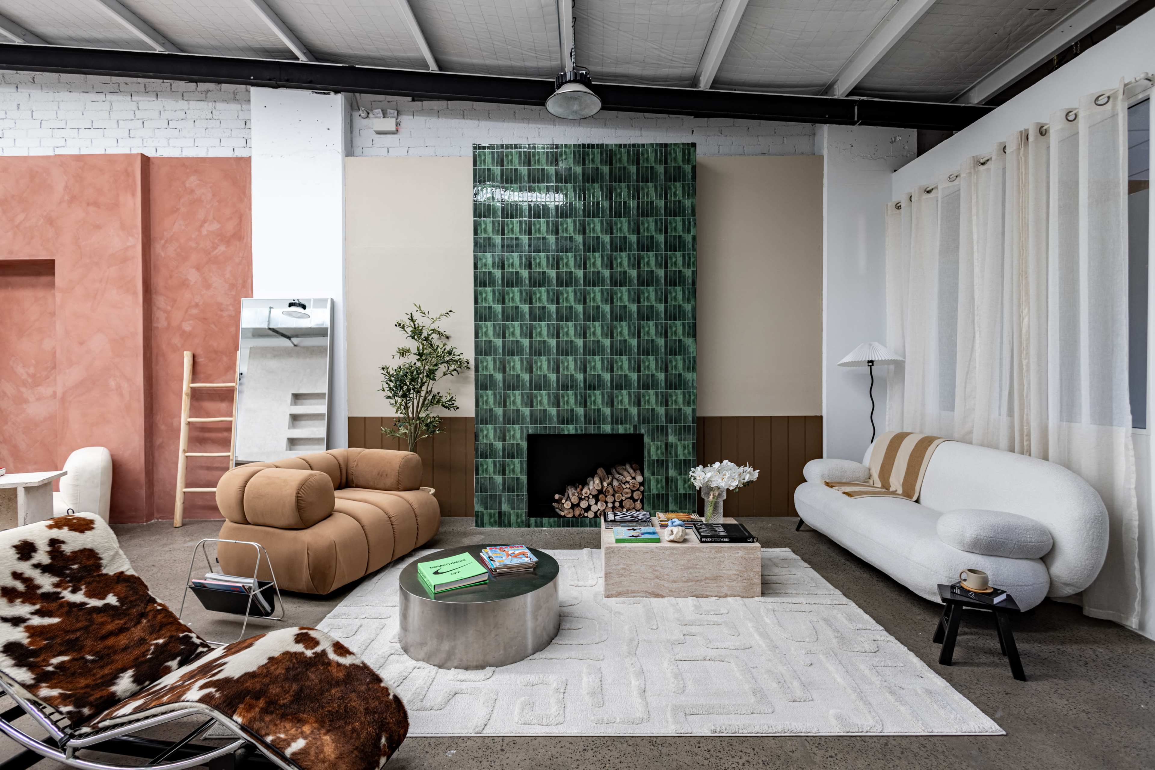 The image depicts a modern living room featuring a mix of furniture styles, a green tiled fireplace, and large windows with sheer curtains.