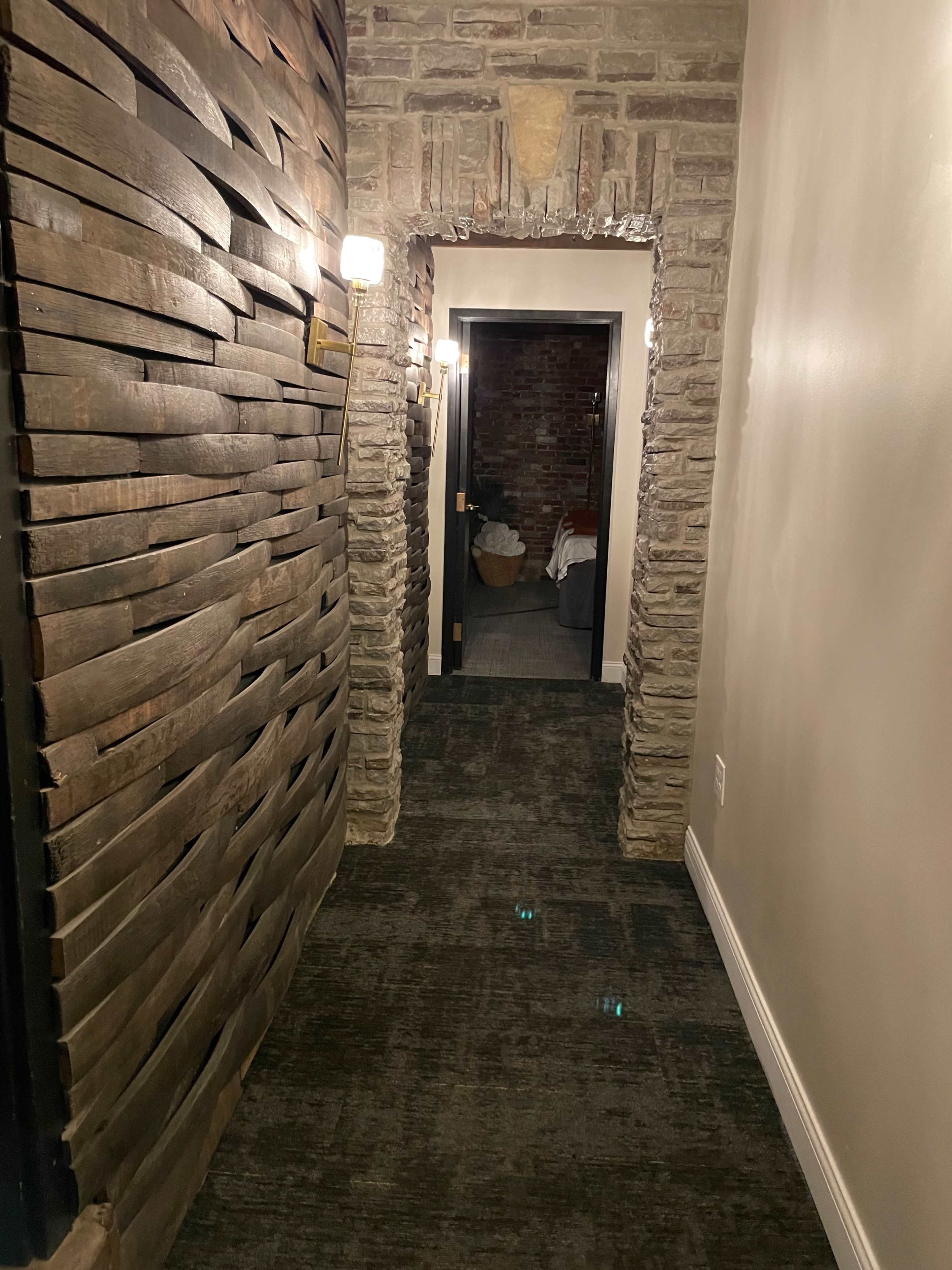 A narrow hallway with textured wooden walls, leading to a dark door at the far end.