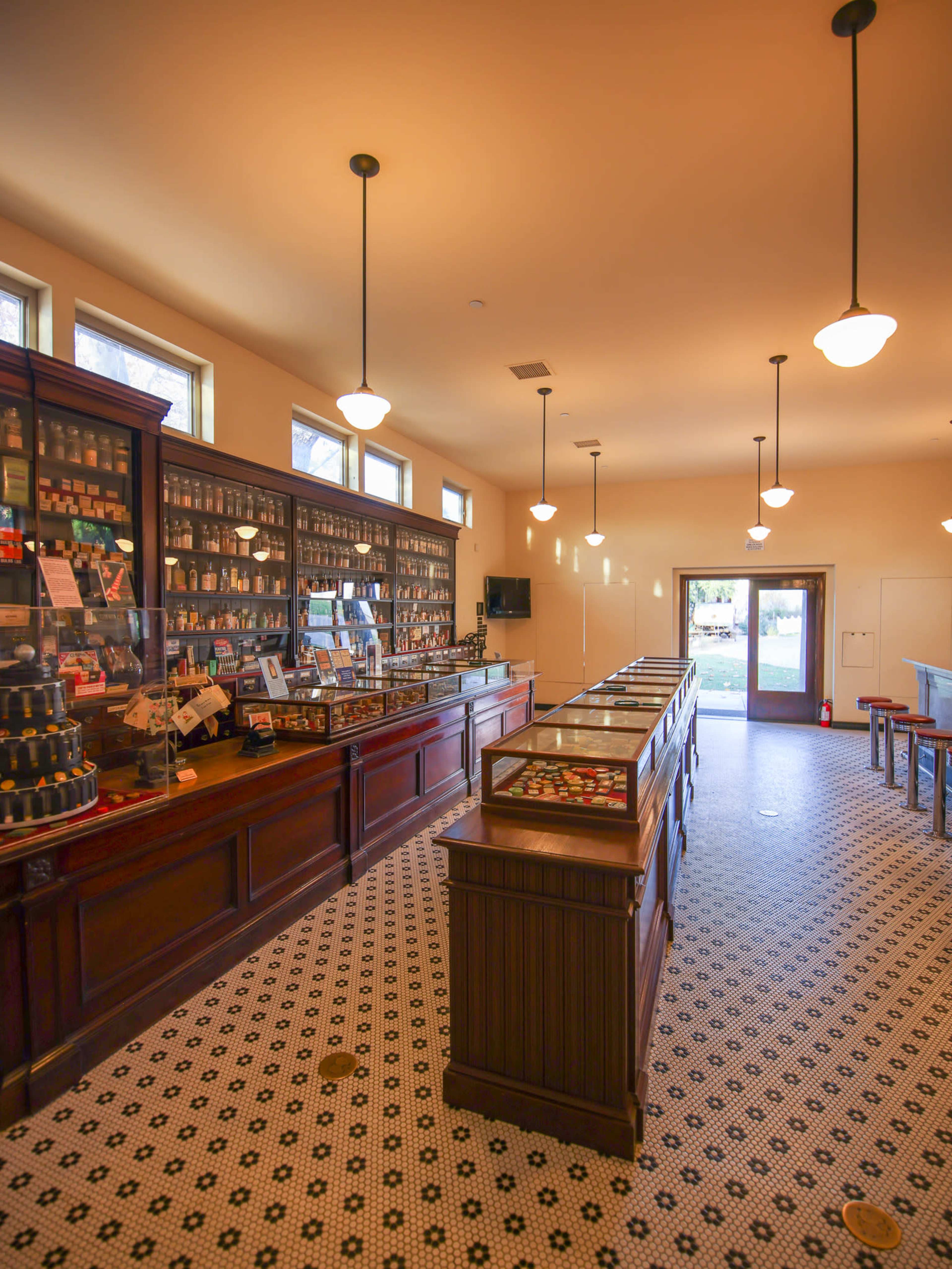 The interior of a vintage-style shop with wooden display cases, shelves of various products, and large windows allowing natural light.