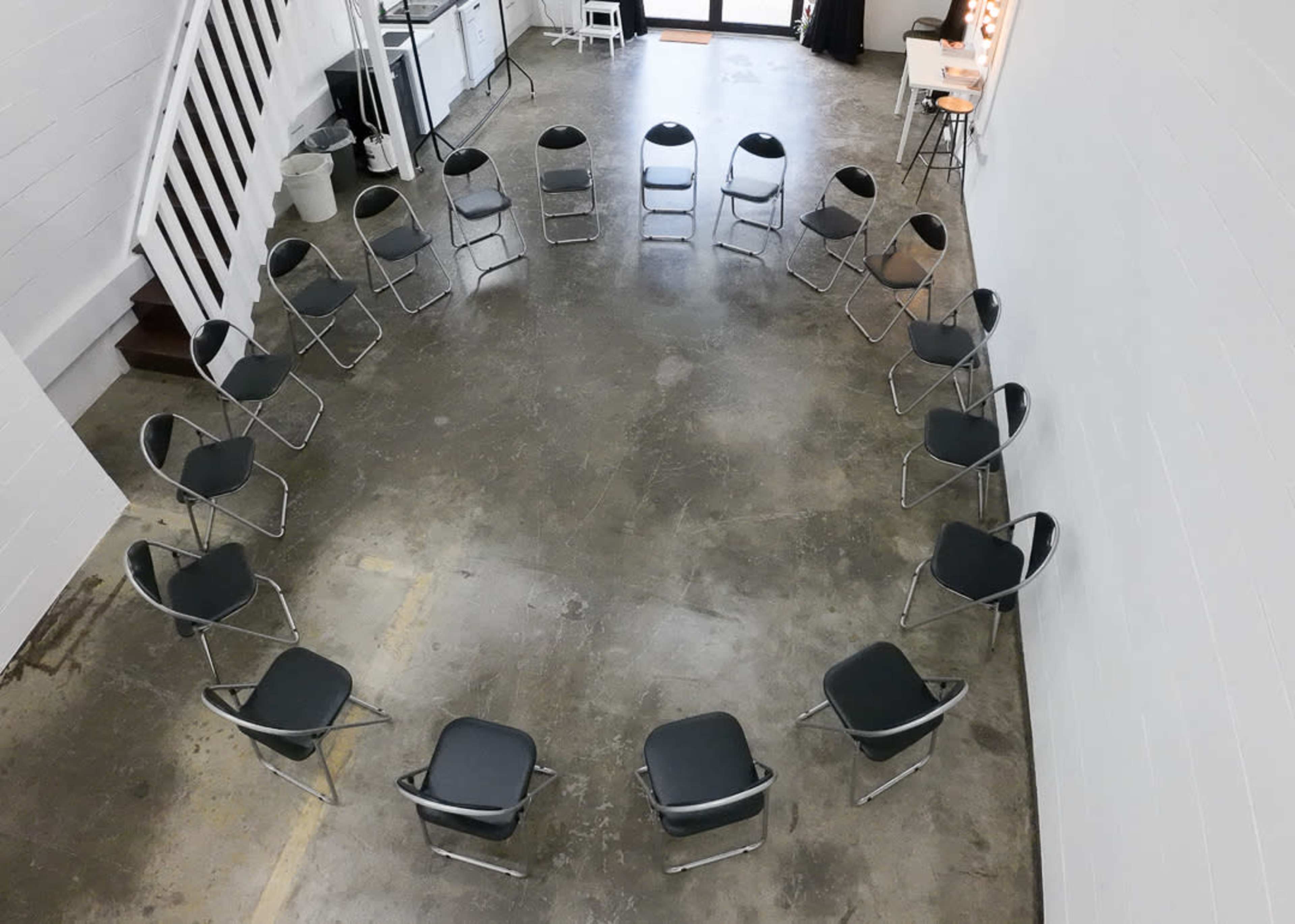 A circular arrangement of metal chairs placed on a concrete floor in a spacious room.