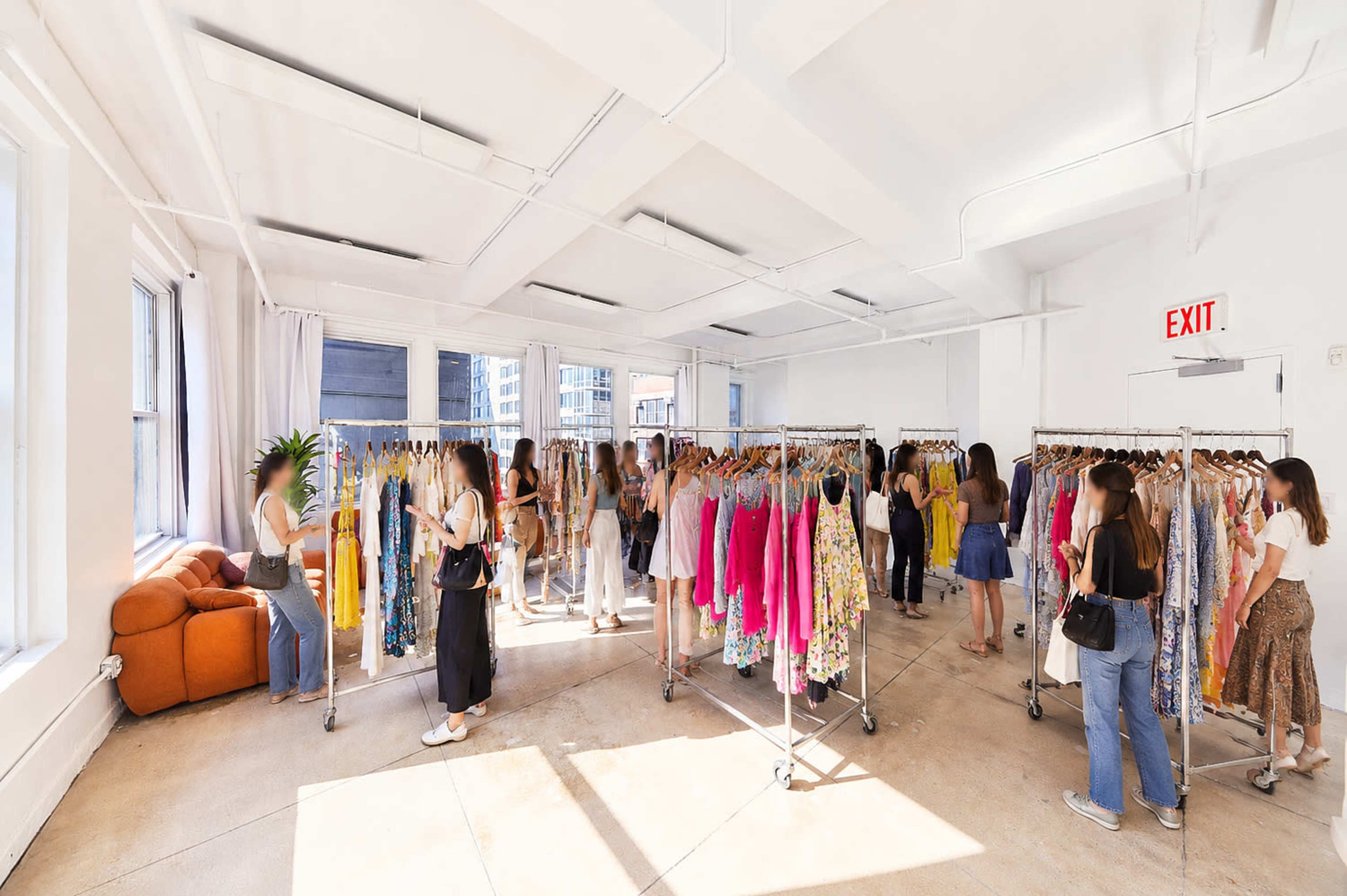 The image shows a spacious boutique filled with multiple clothing racks displaying colorful garments, while several shoppers browse the selection.