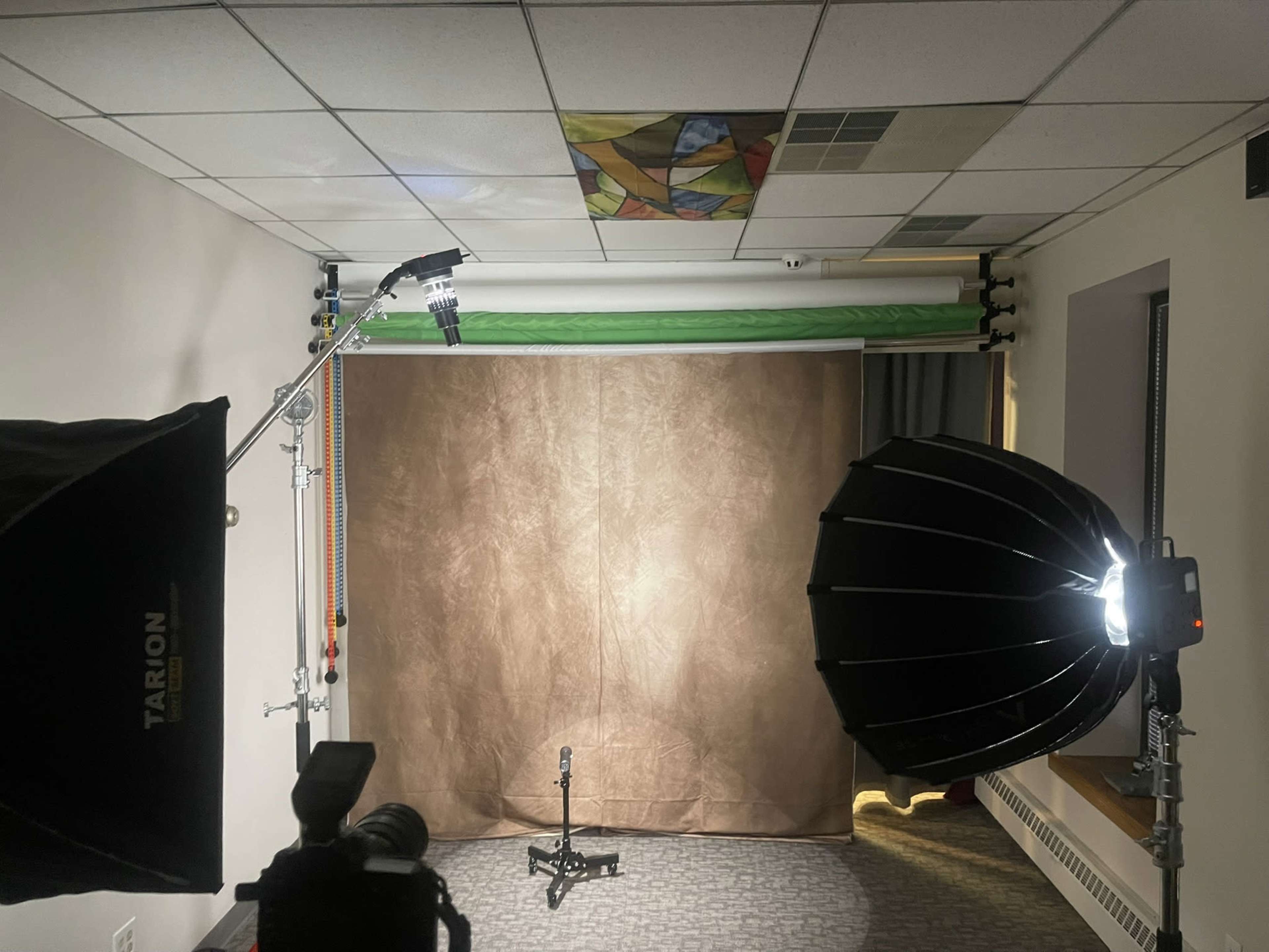 The image shows a photography setup featuring a brown backdrop, studio lights on either side, and a camera positioned in the foreground.