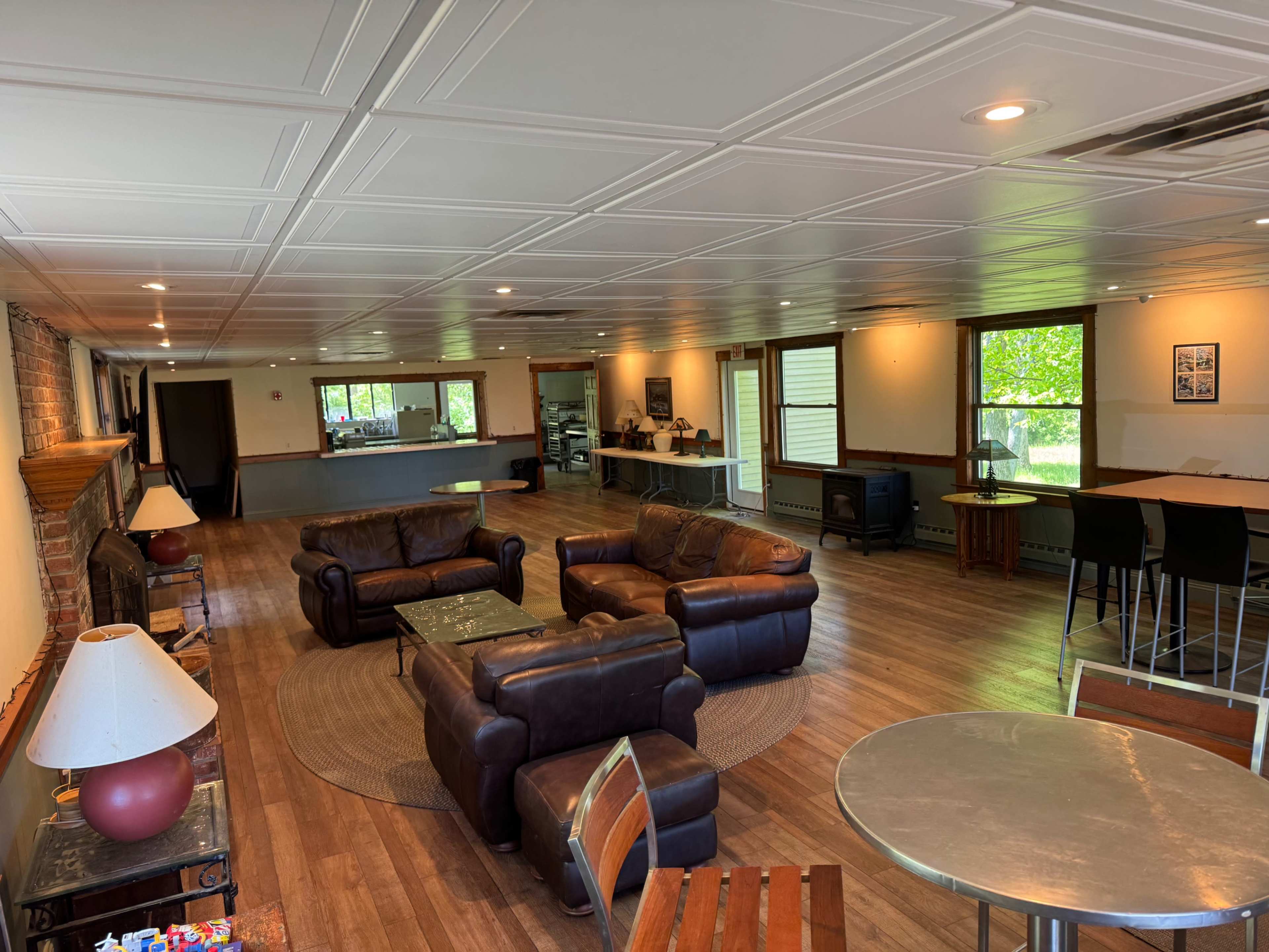 The image shows a spacious, well-lit room with leather couches, a dining table, and a kitchen area in the background.