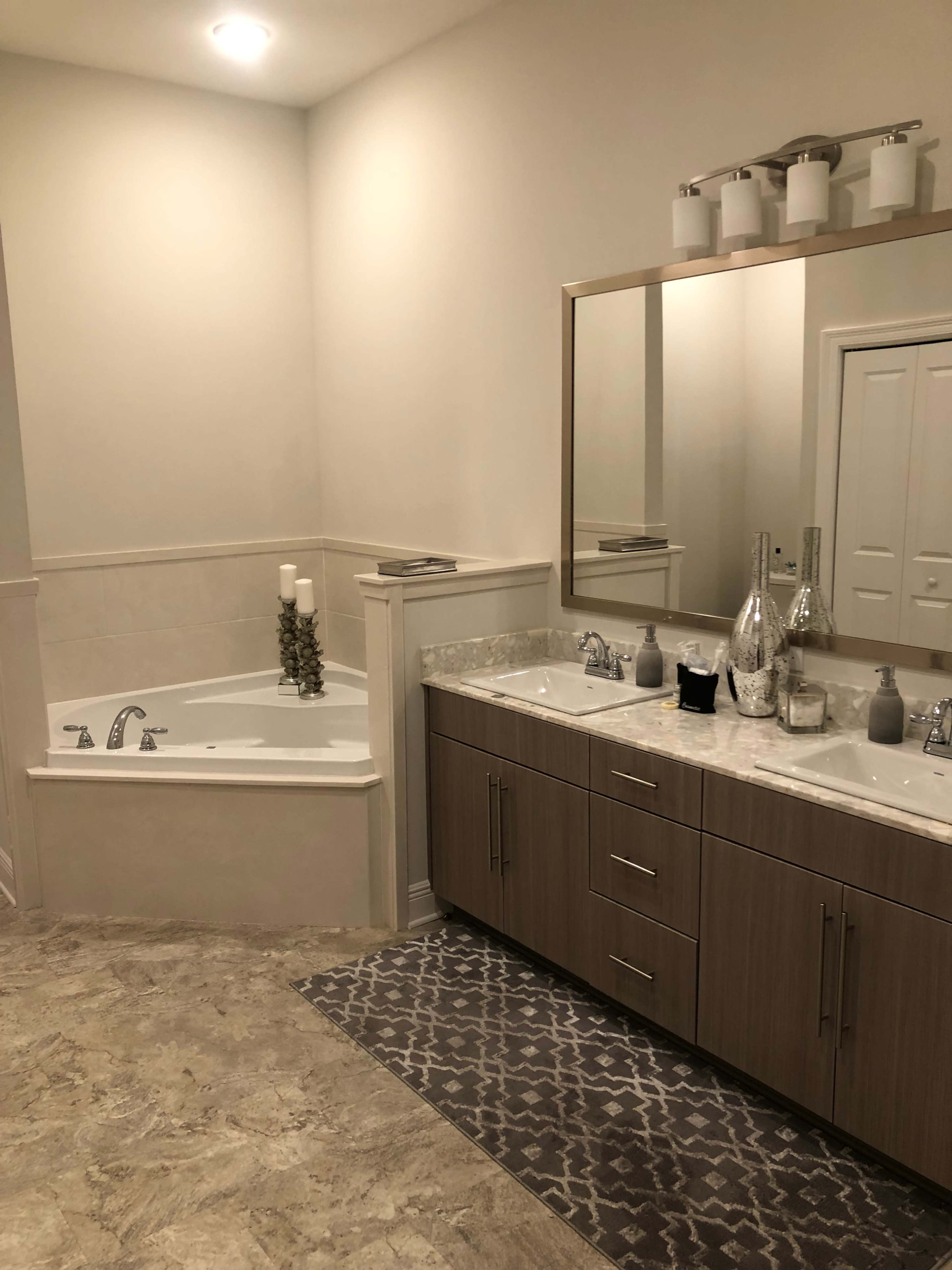 The image shows a modern bathroom featuring a freestanding bathtub, a double sink vanity with a marble countertop, and a large mirror above the sinks.
