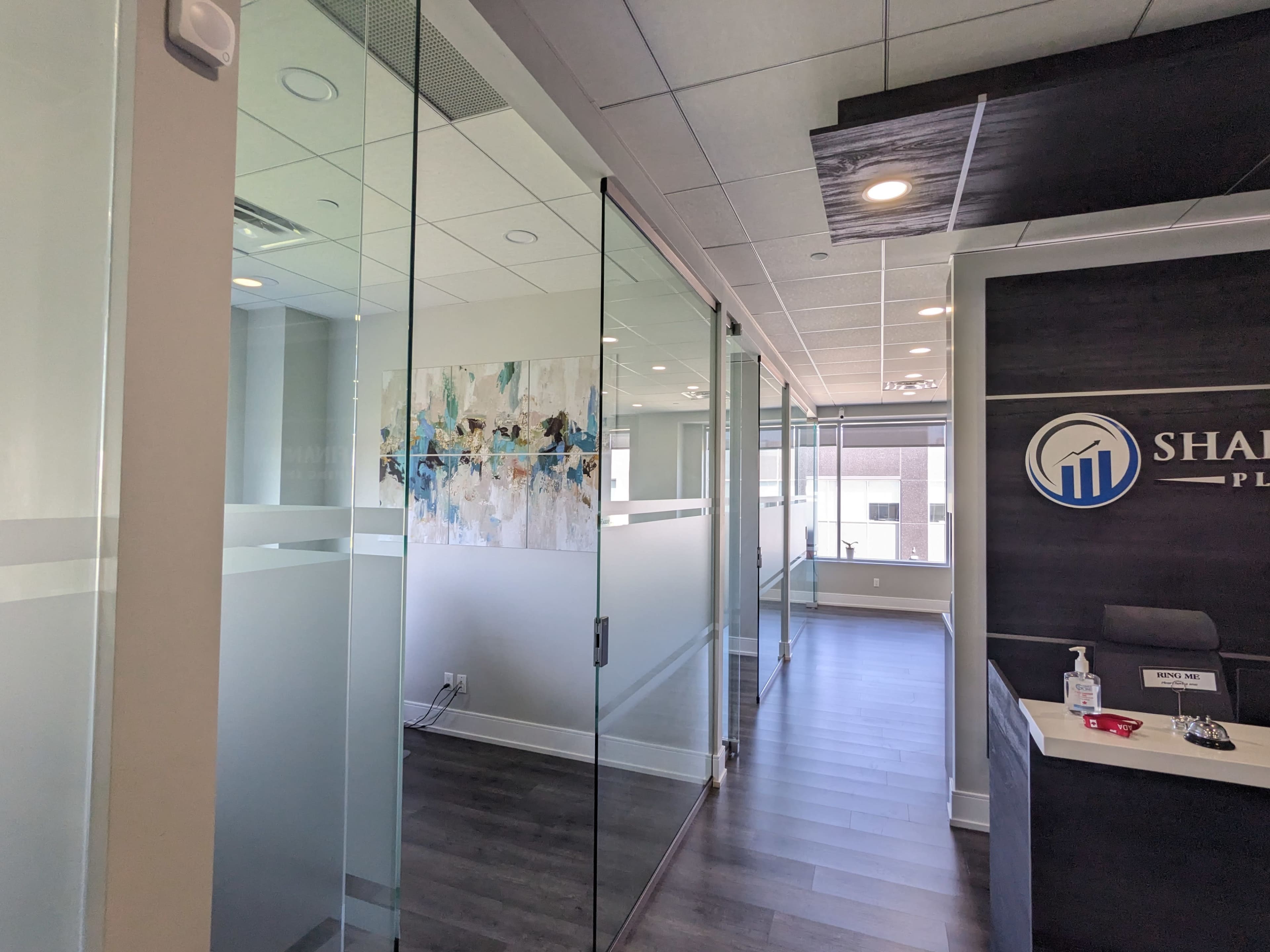 A modern office space with glass-walled meeting rooms and a reception area featuring a logo.