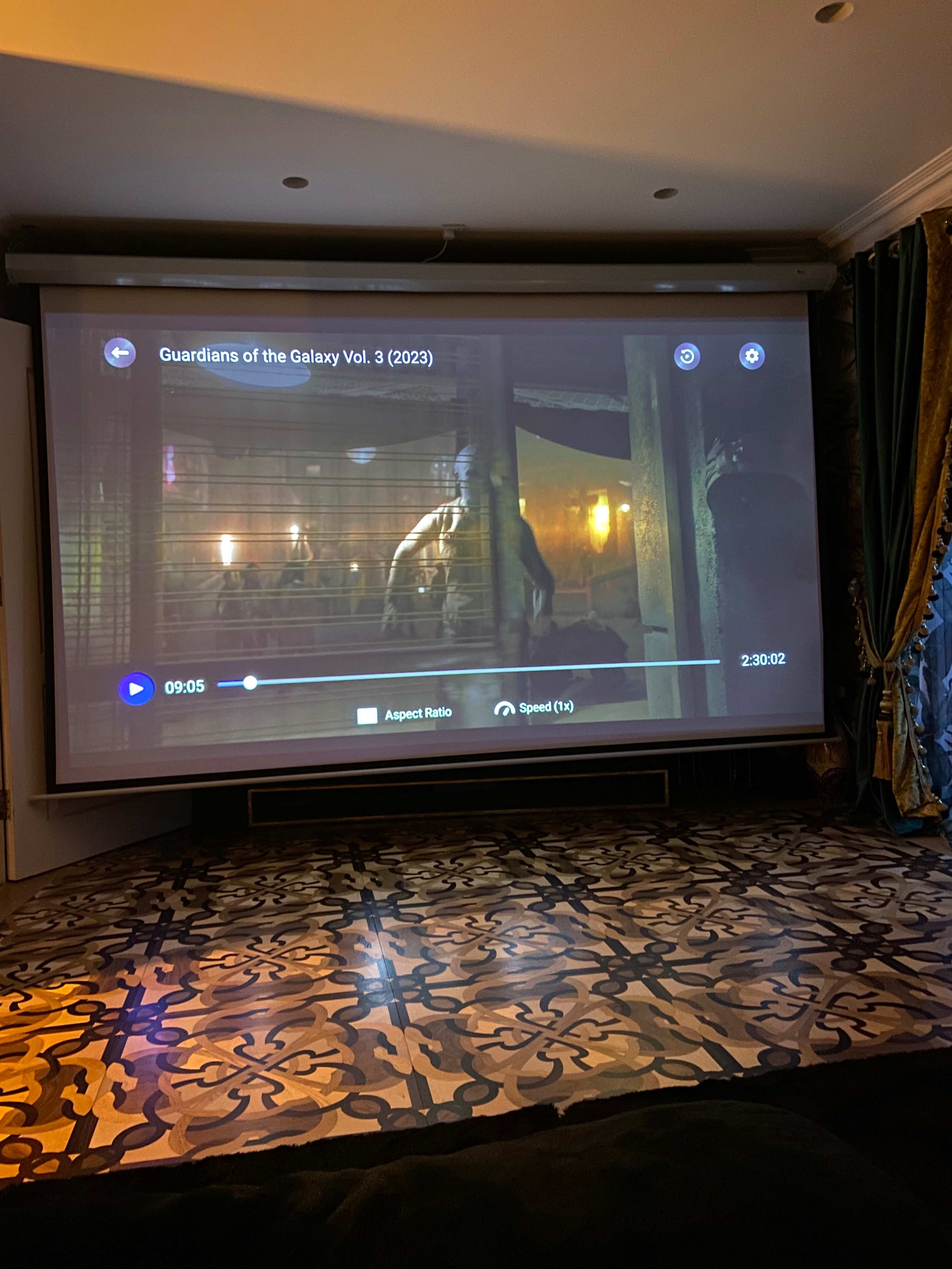 A large projector screen displays a scene from "Guardians of the Galaxy Vol. 3" in a home theater setting.