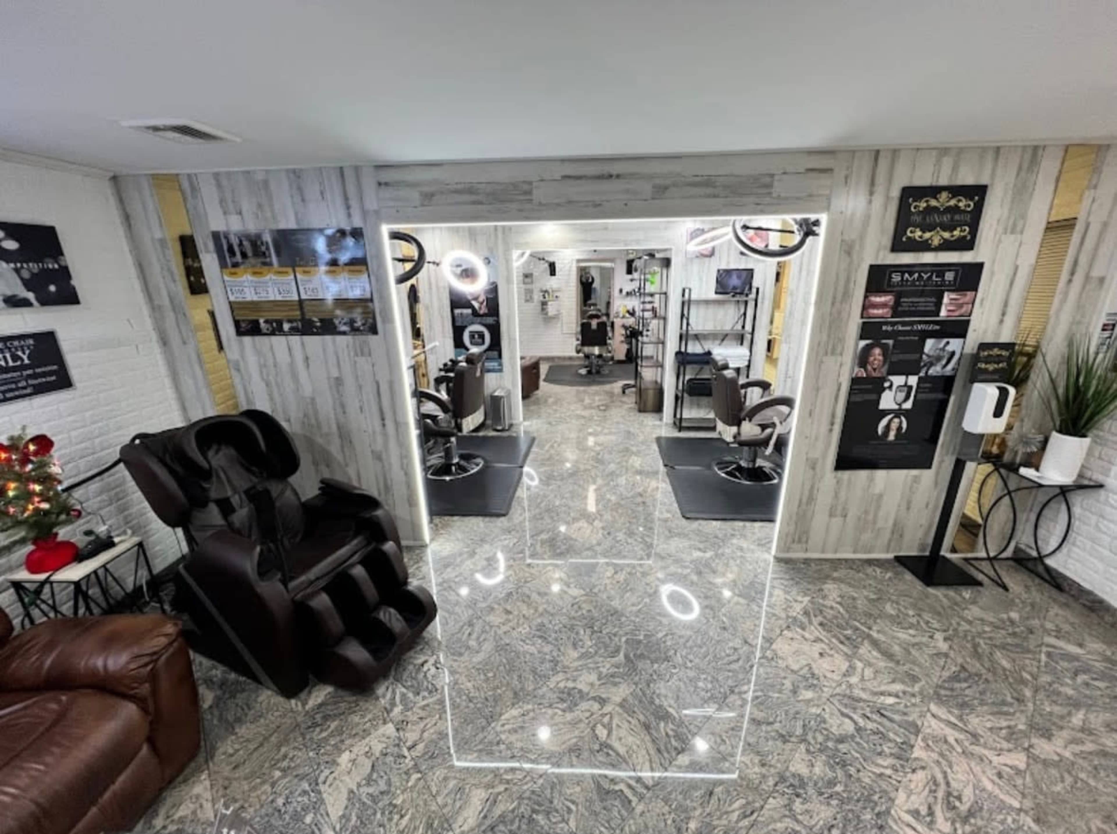 The image shows the interior of a modern hair salon featuring sleek styling chairs, a reception area, and illuminated mirrors, with decor and promotional posters on the walls.