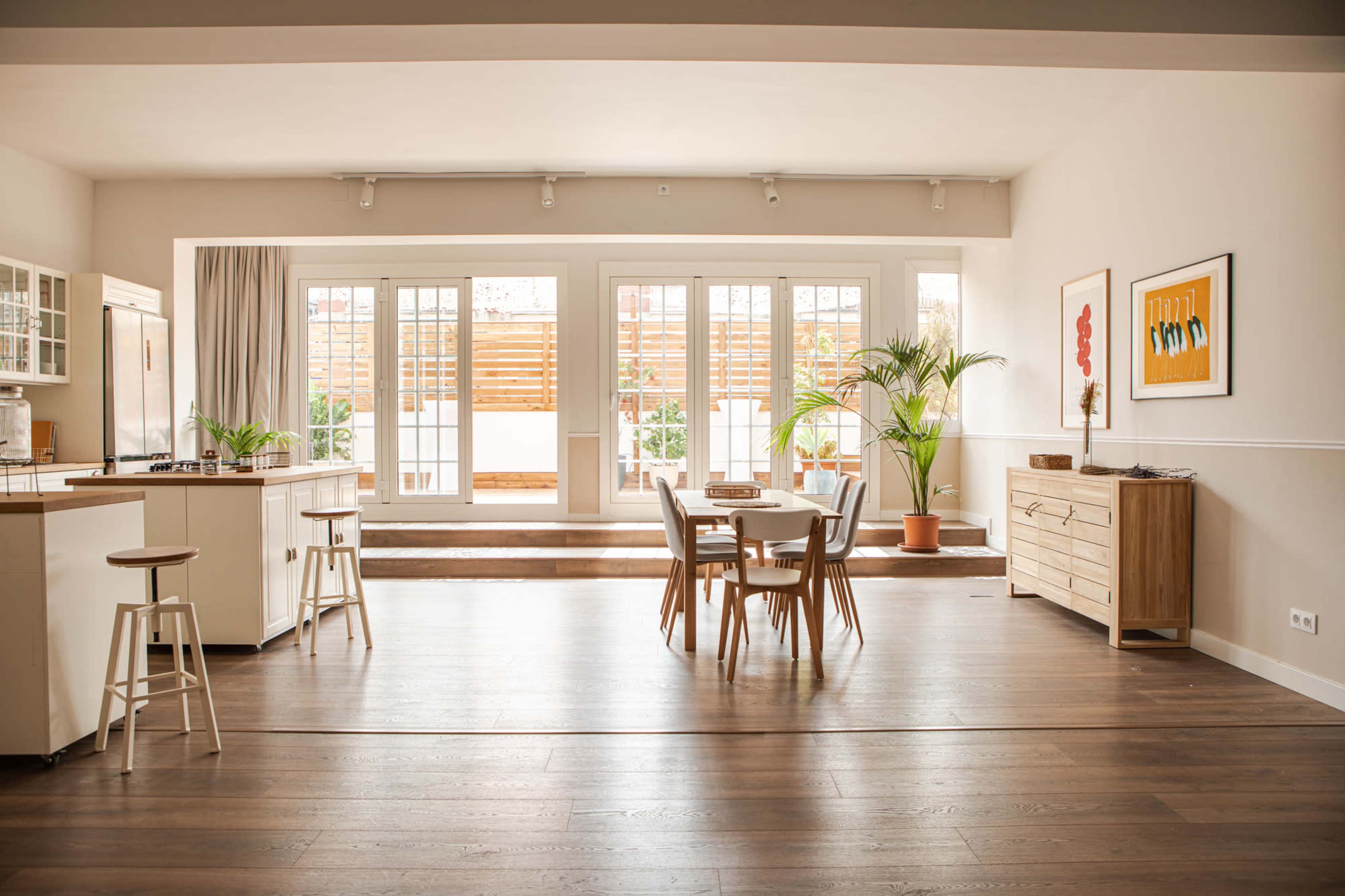 A spacious, well-lit open-concept kitchen and dining area features a wooden table, chairs, and large sliding doors leading to an outdoor space.