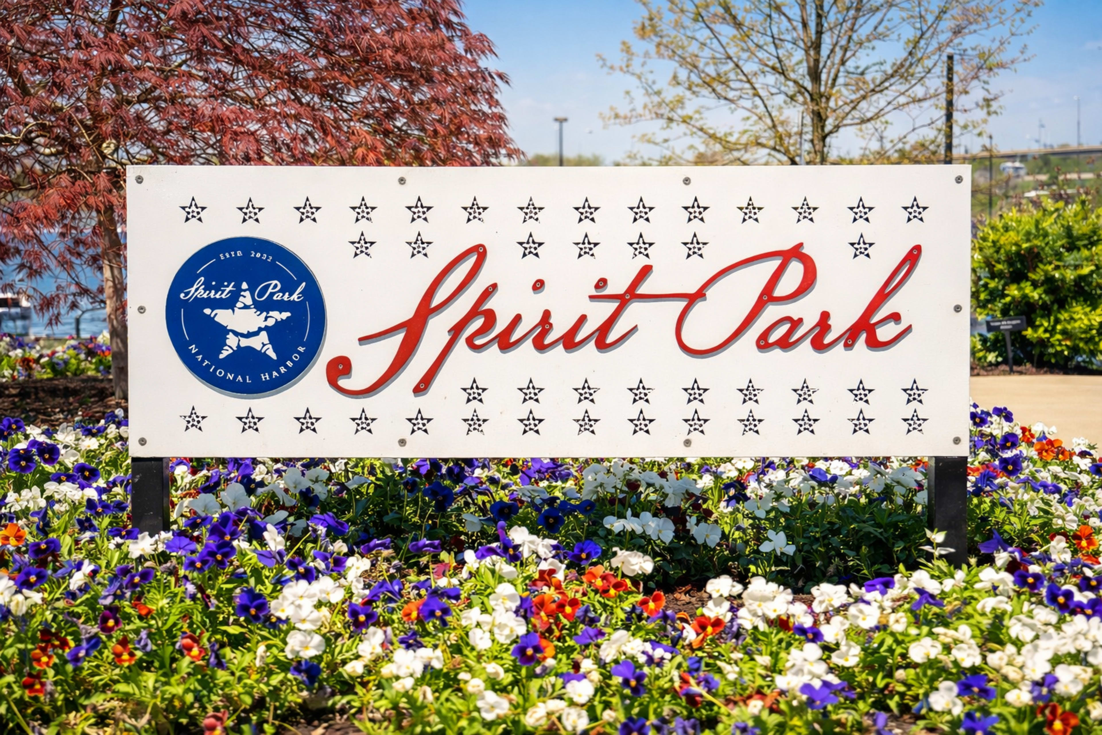 The image shows a sign for "Spirit Park" surrounded by colorful flowers.