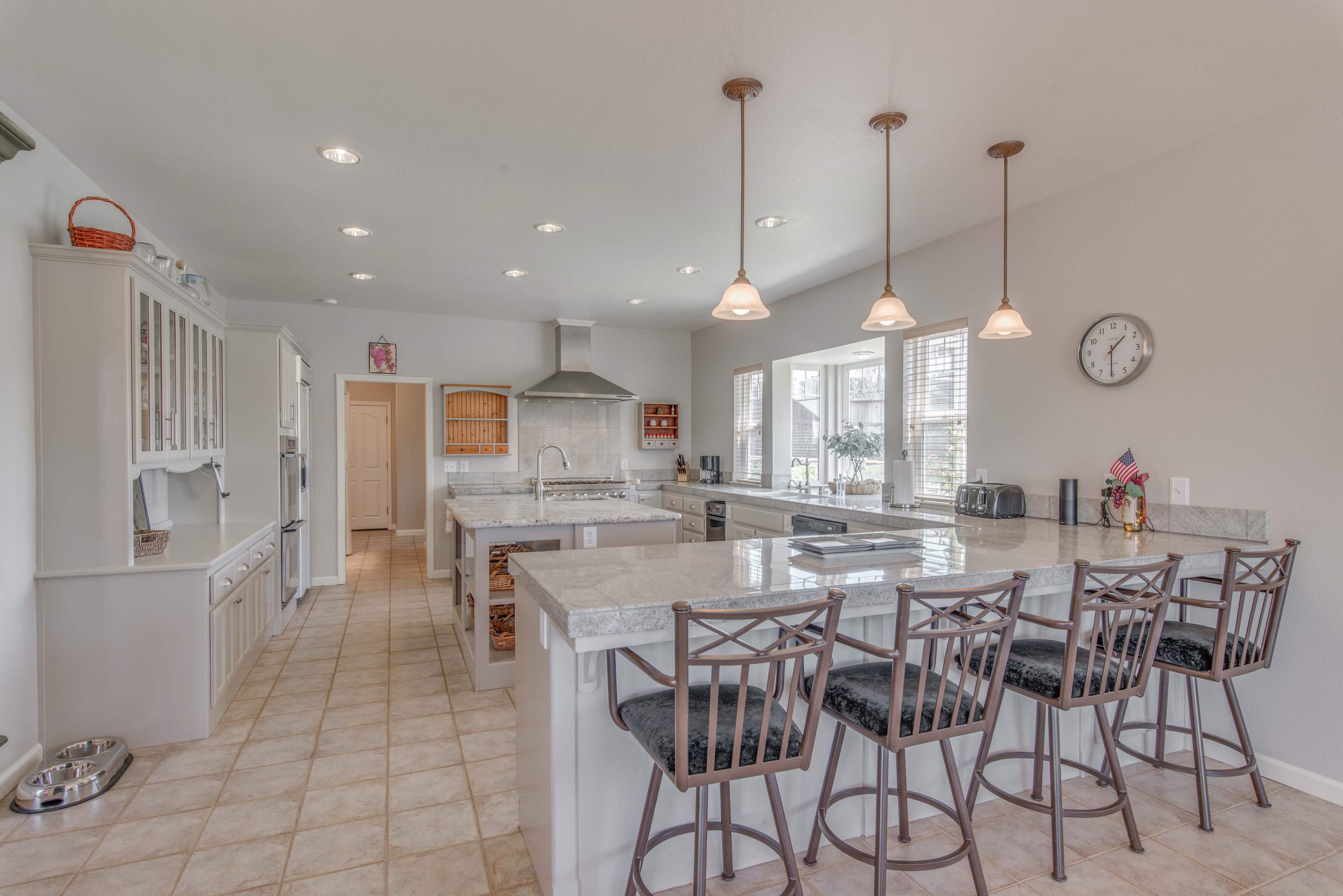 A spacious kitchen with a central island featuring bar stools, modern appliances, and light-colored cabinetry.
