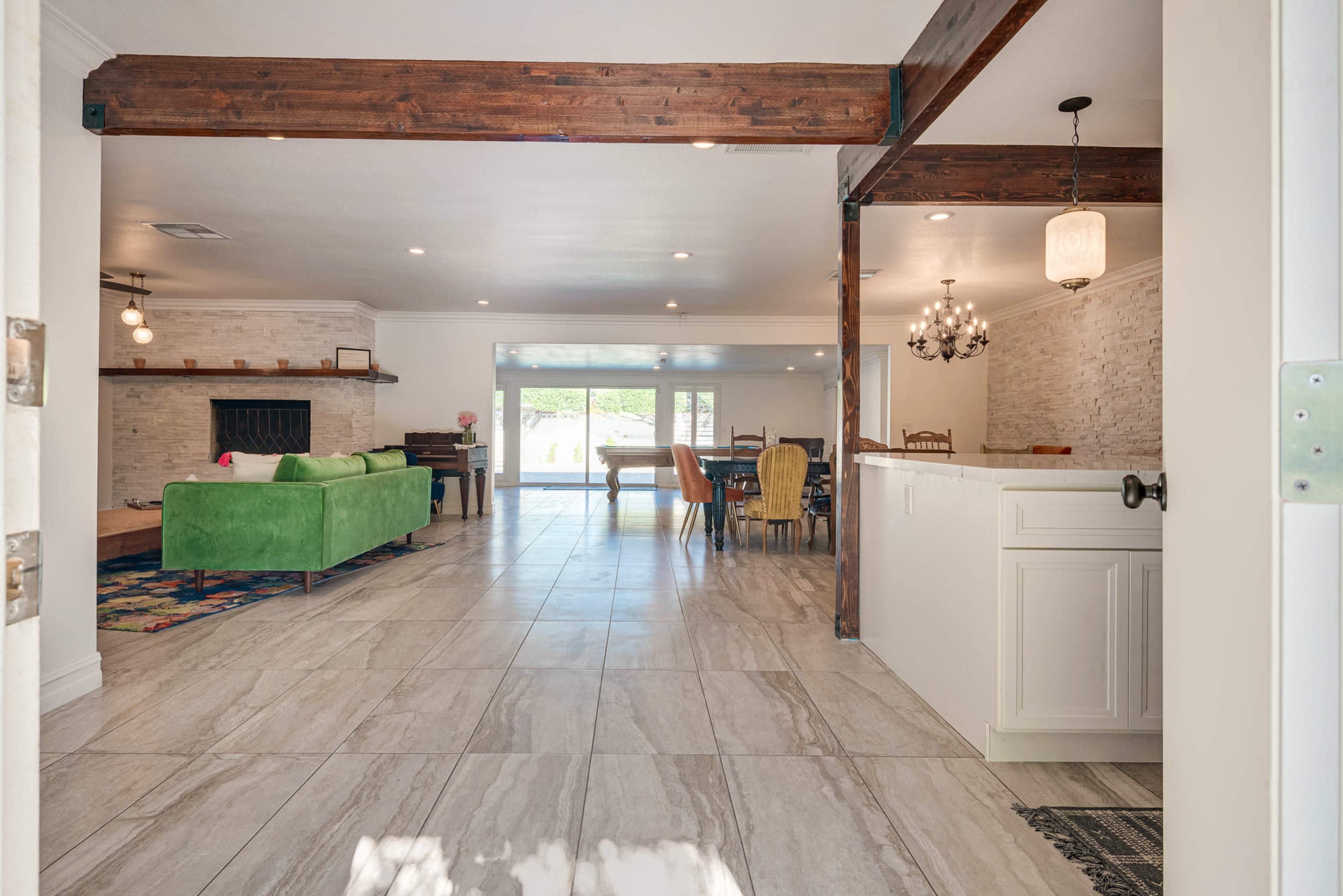 A spacious, open-concept living area featuring a green sofa, a dining table, and large windows allowing natural light to enter.