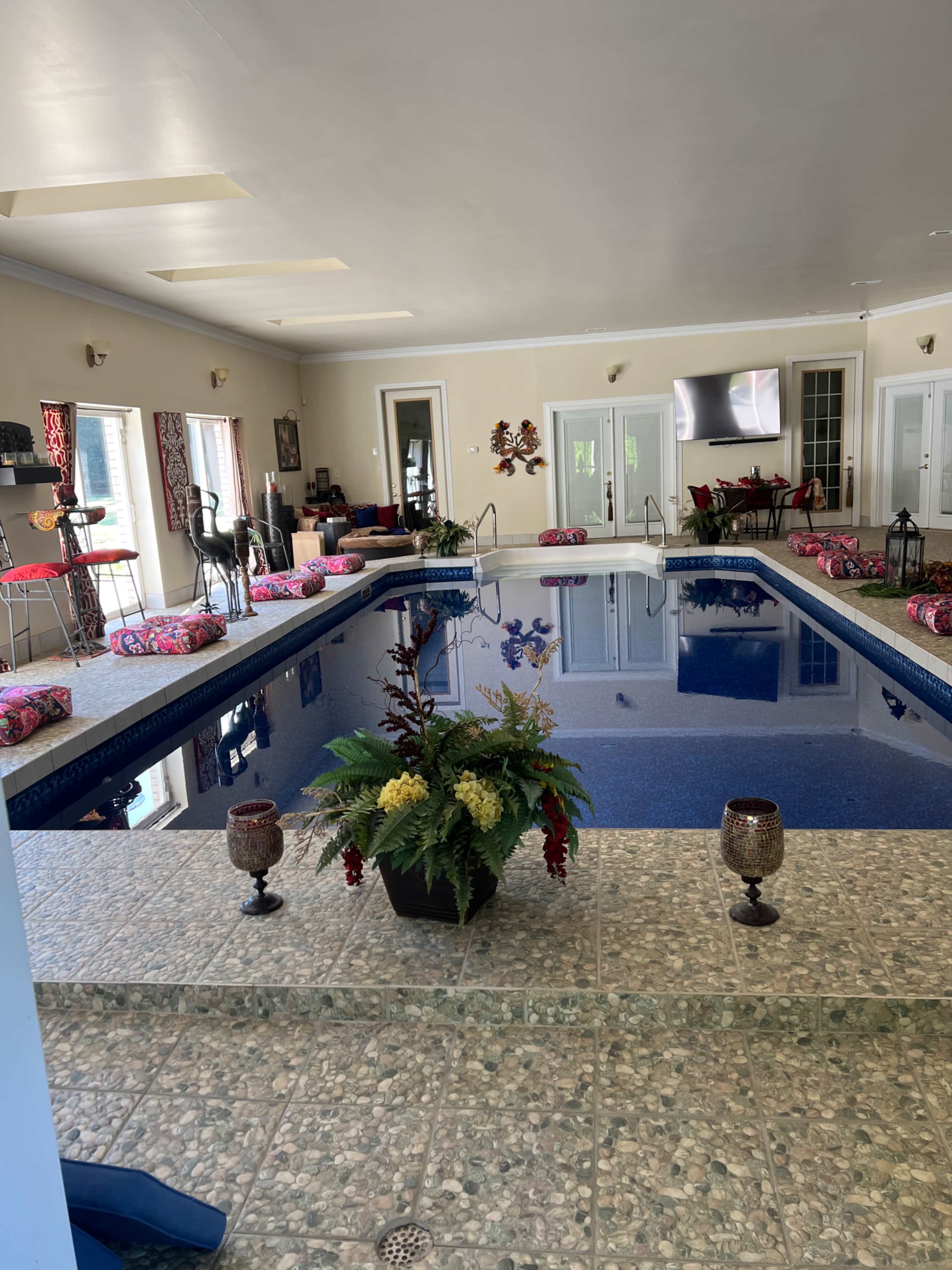 An indoor swimming pool surrounded by decorative plants and seating areas.