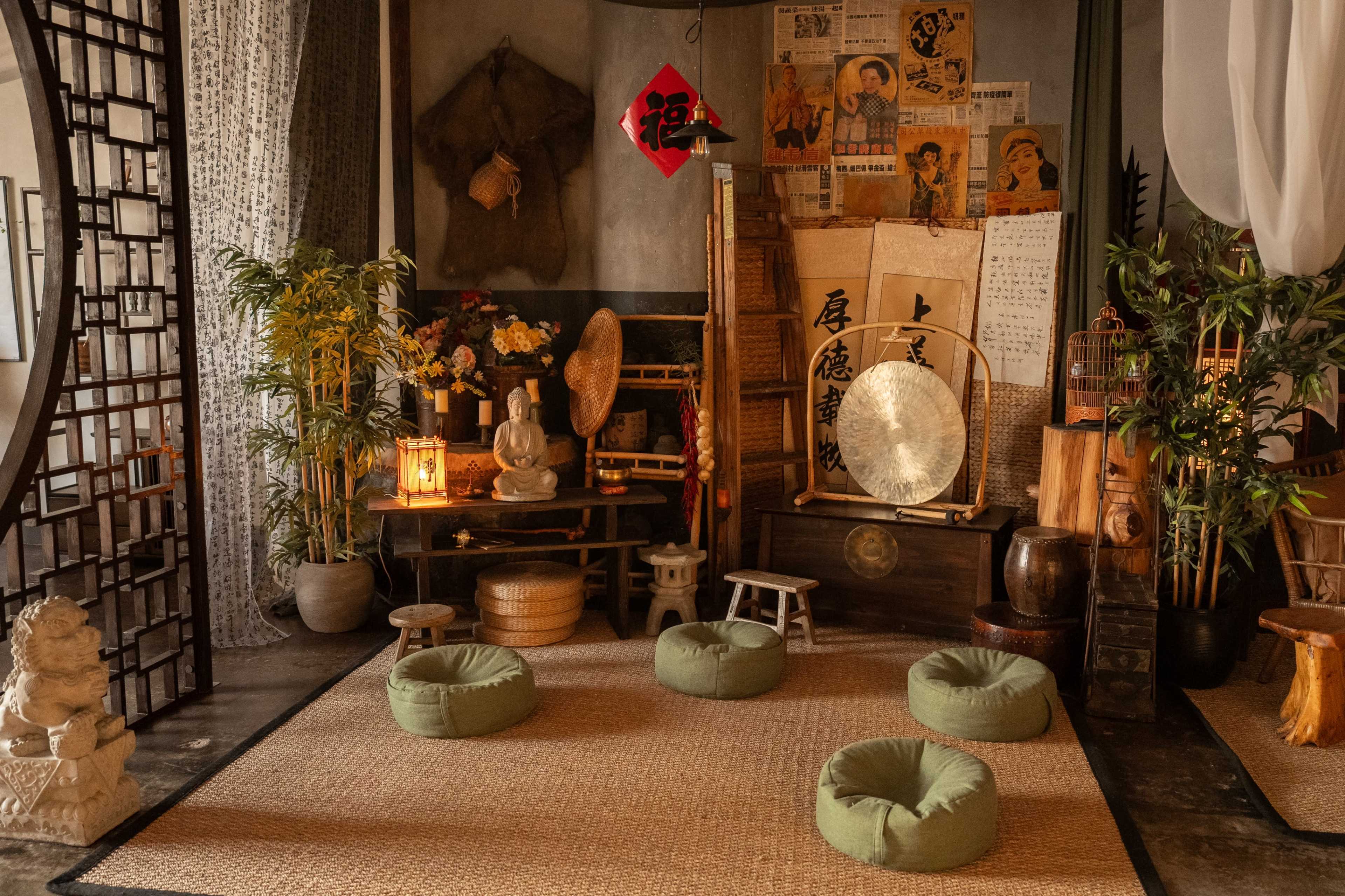A serene interior space designed for meditation, featuring round floor cushions, decorative plants, and traditional Asian decor elements.