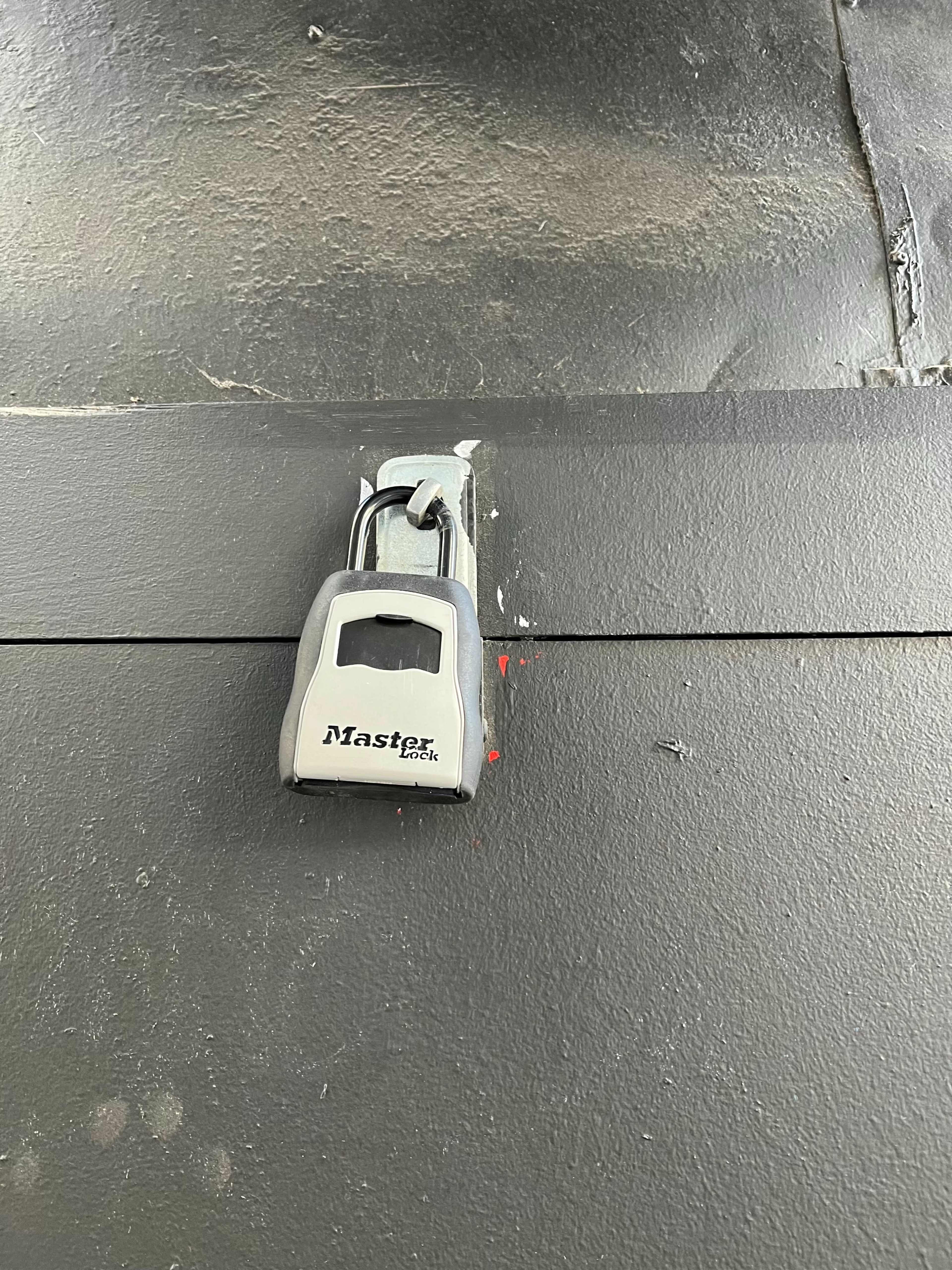 A Master Lock is attached to a metal surface, secured in a closed position.
