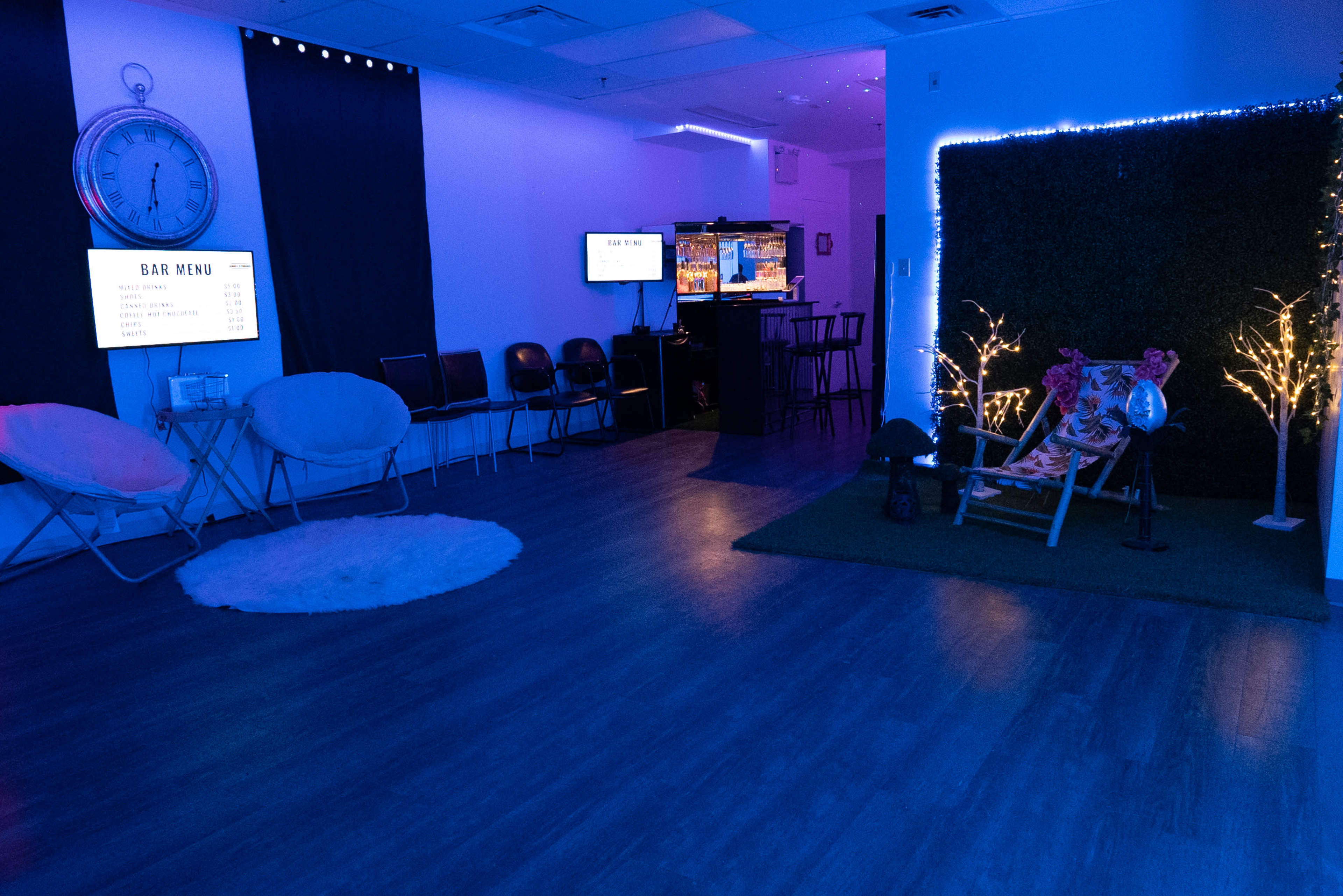 The room features a bar area with a menu display, several chairs, and a small section with decorative lights and seating.