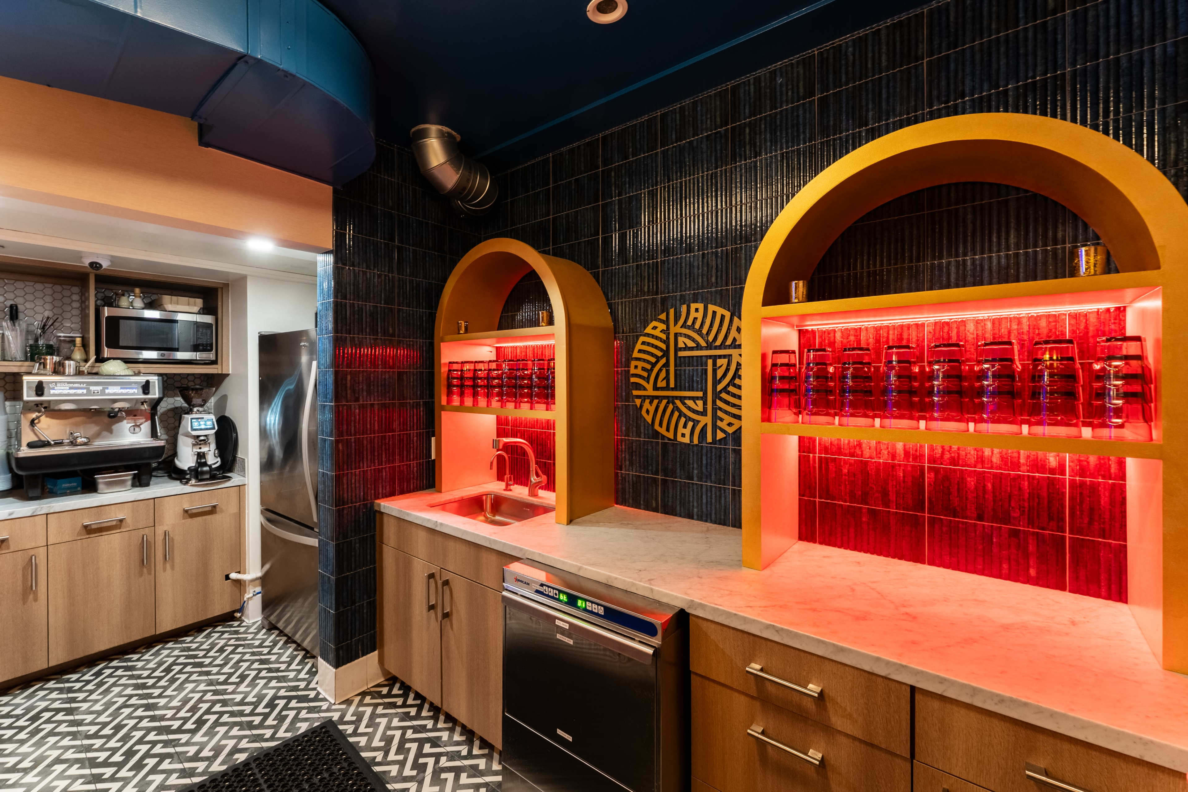 The image shows a modern kitchen with a sleek design featuring curved arches, a sink area with warm backlighting, and a patterned tile floor.