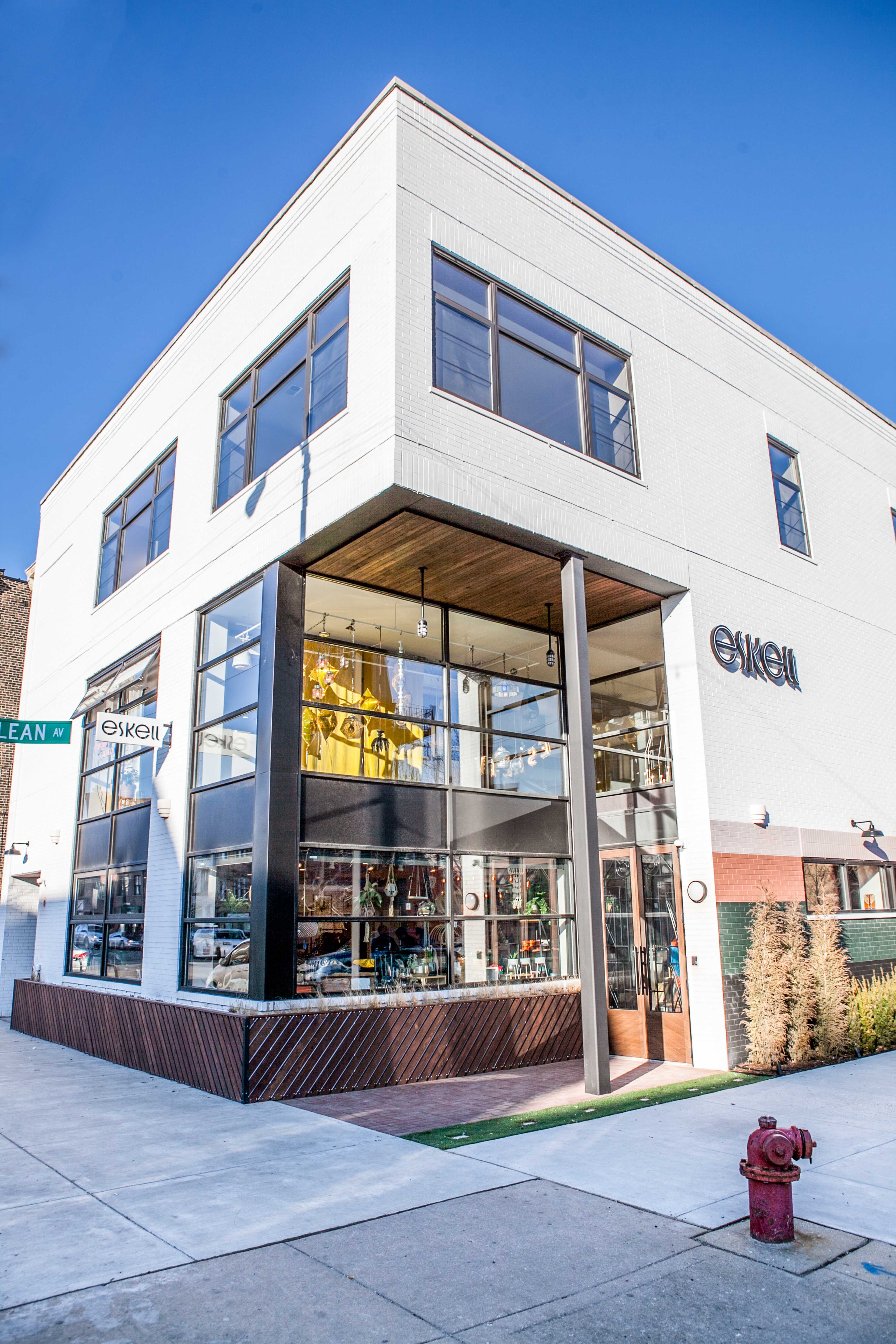 A modern, two-story retail building with large glass windows and a corner entrance, located at a street intersection.