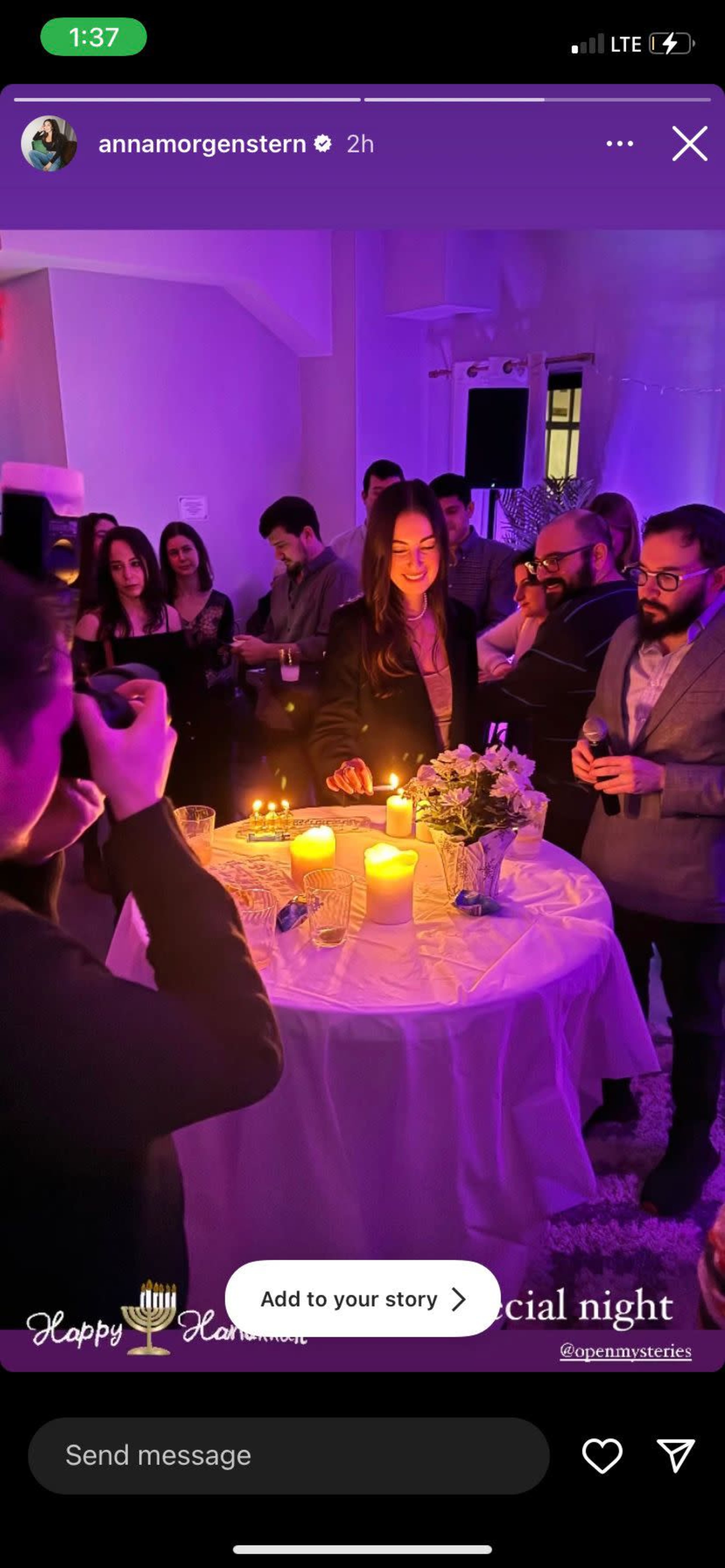 A group of people gathers around a table with candles and decorations during a celebratory event.
