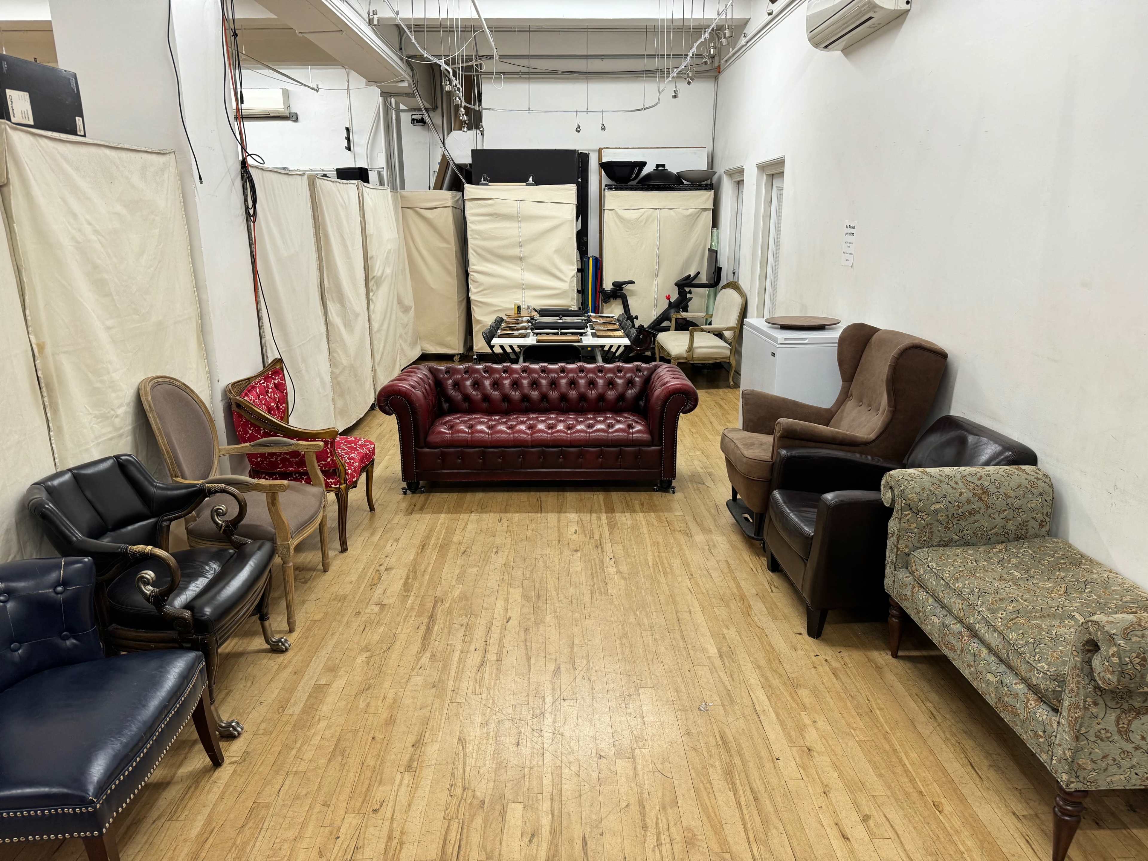 The image shows a narrow room featuring several different upholstered chairs and couches arranged along the walls.