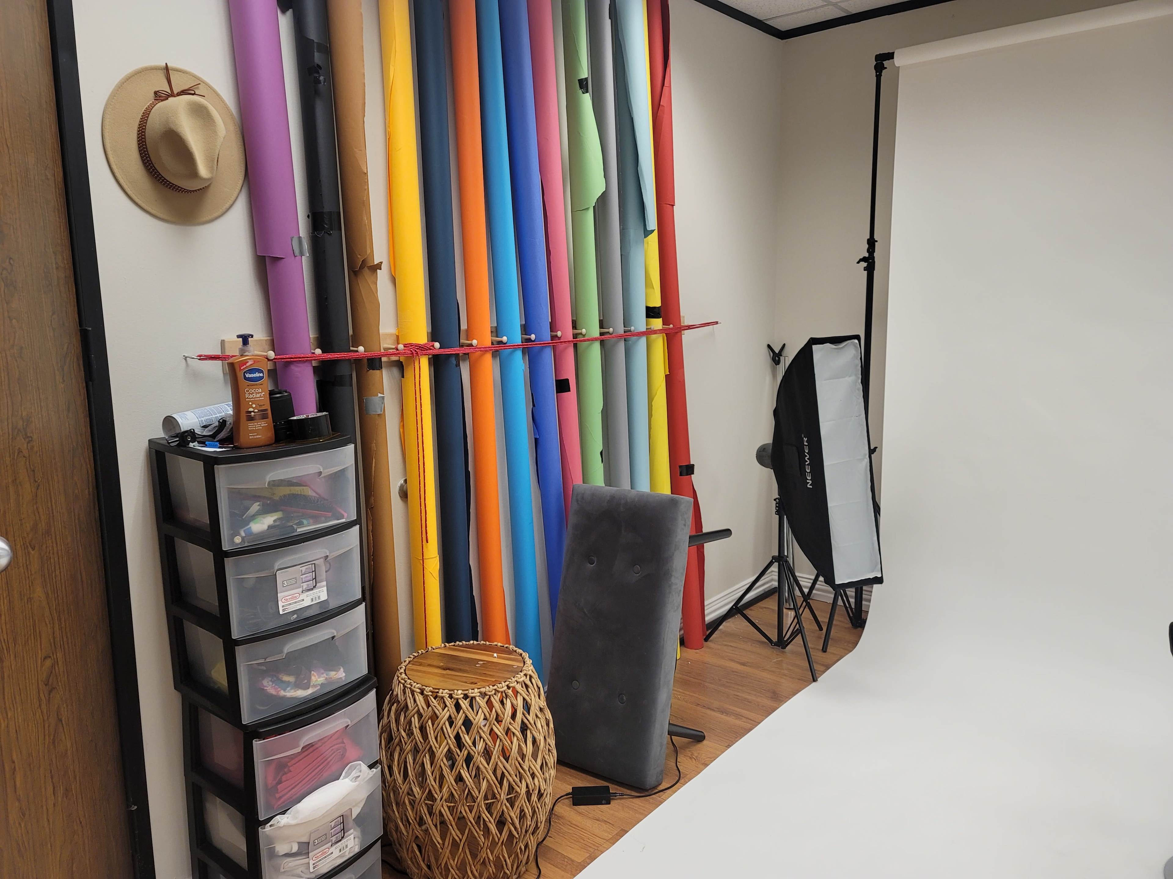 A photography studio with a backdrop of colorful rolls of paper, a storage unit, and lighting equipment.