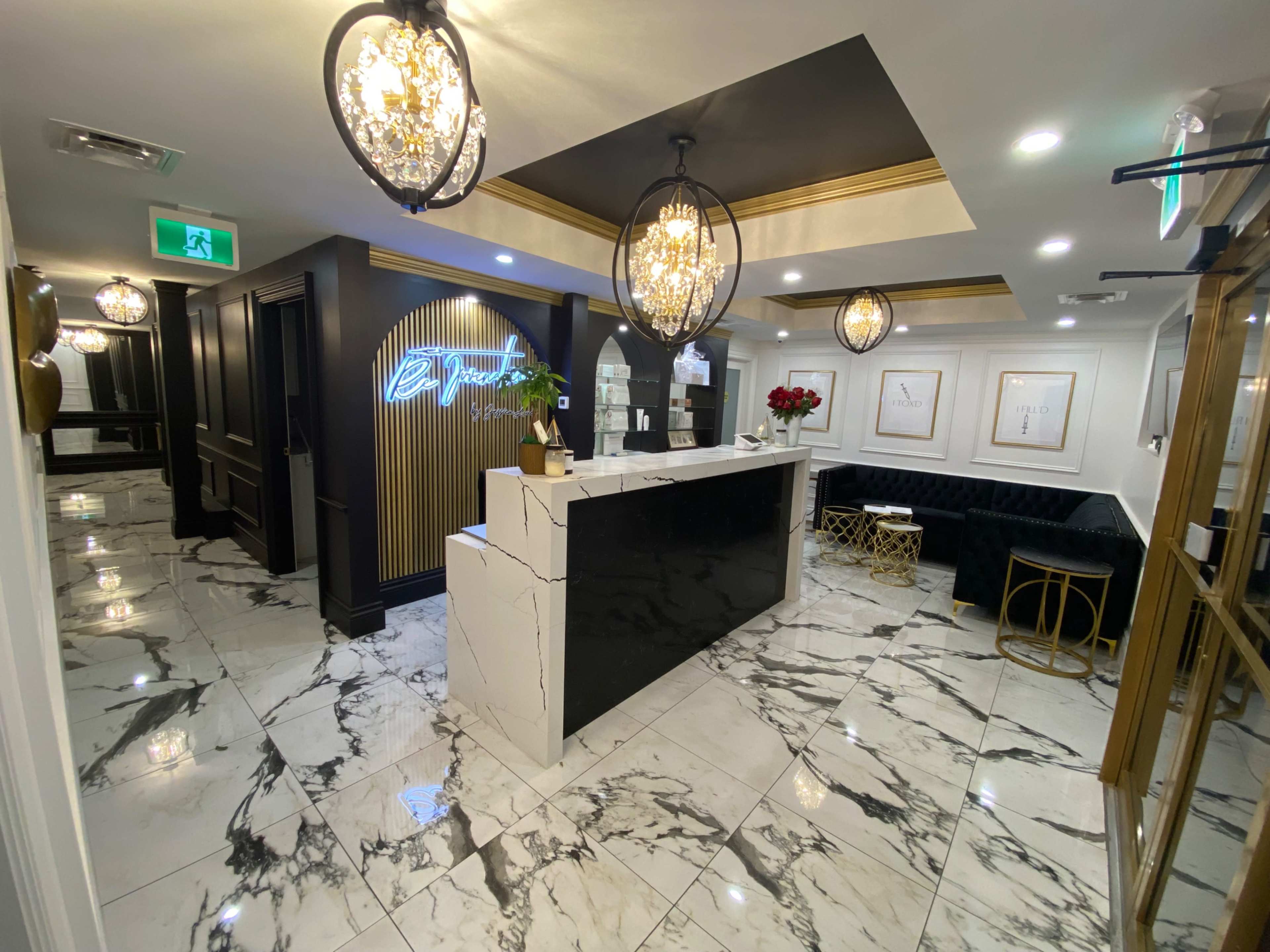 A modern reception area with black and white marble flooring, a stylistic front desk, and decorative lighting fixtures.
