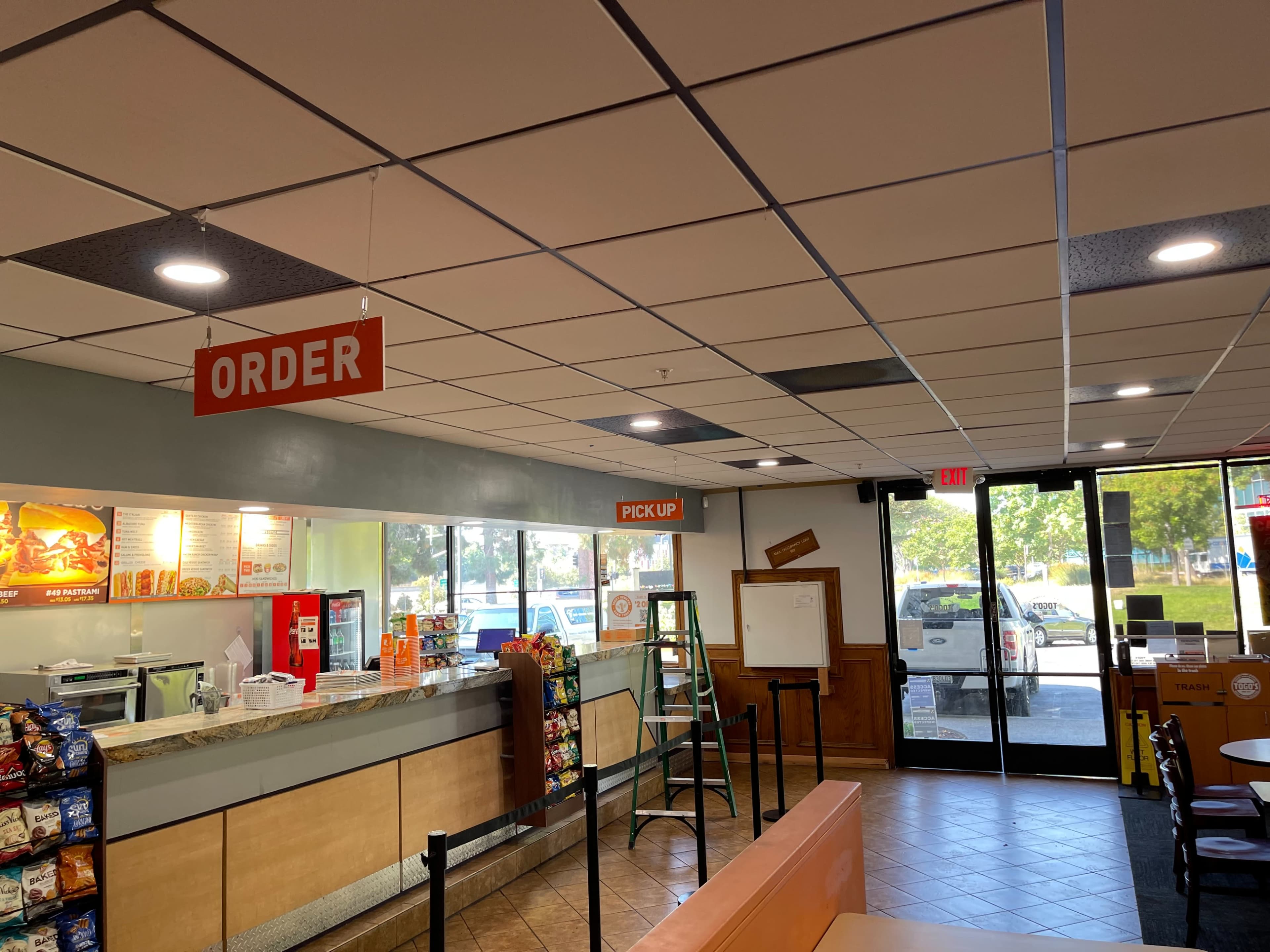 An interior of a restaurant with visible signs indicating "ORDER" and "PICKUP," along with a counter and seating area.