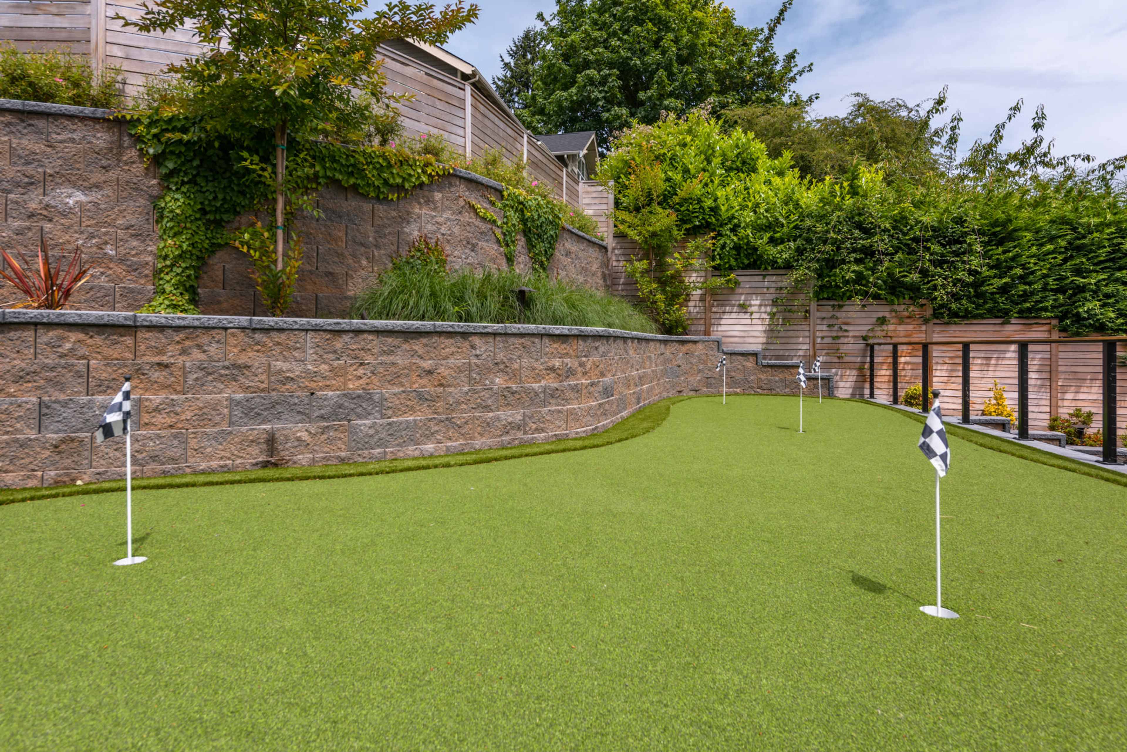 A landscaped area featuring a synthetic grass putting green with small flags marking the holes.