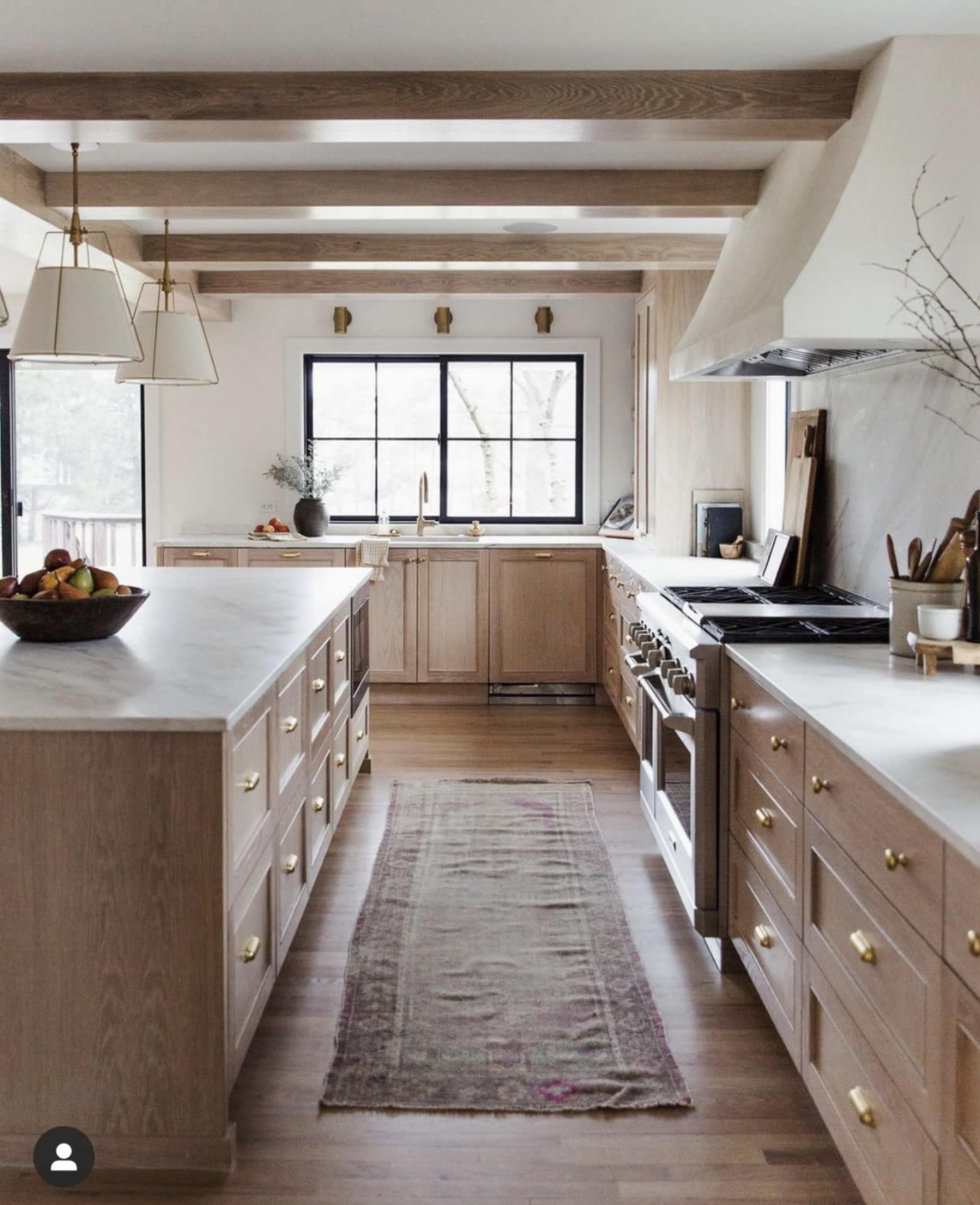 A modern kitchen features wooden cabinetry, a large central island, and a window overlooking a outdoor view.