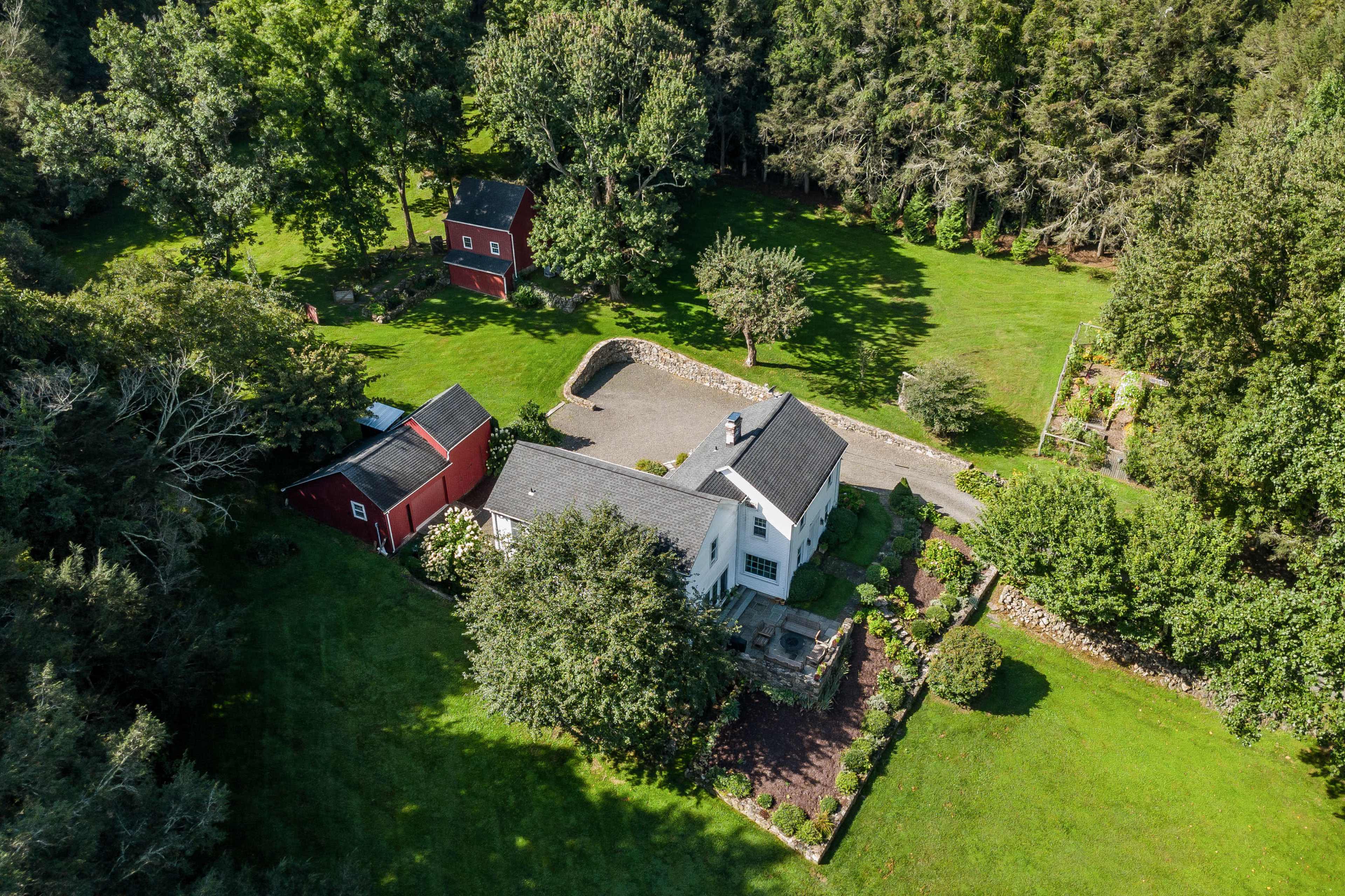 The image shows a large property with a main house and several outbuildings surrounded by lush greenery and trees.