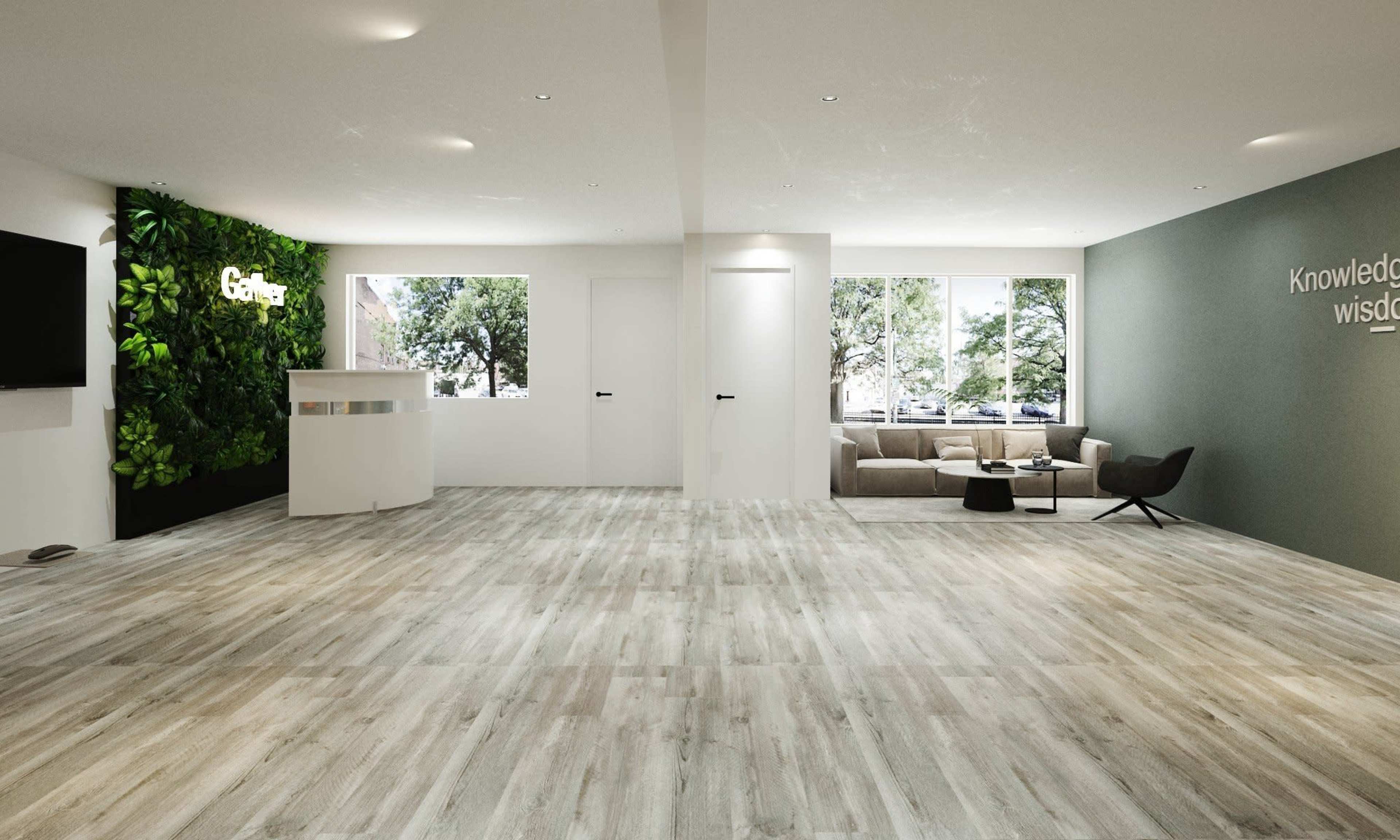 A modern, spacious interior with wooden flooring, a green wall feature, and a seating area beside large windows.