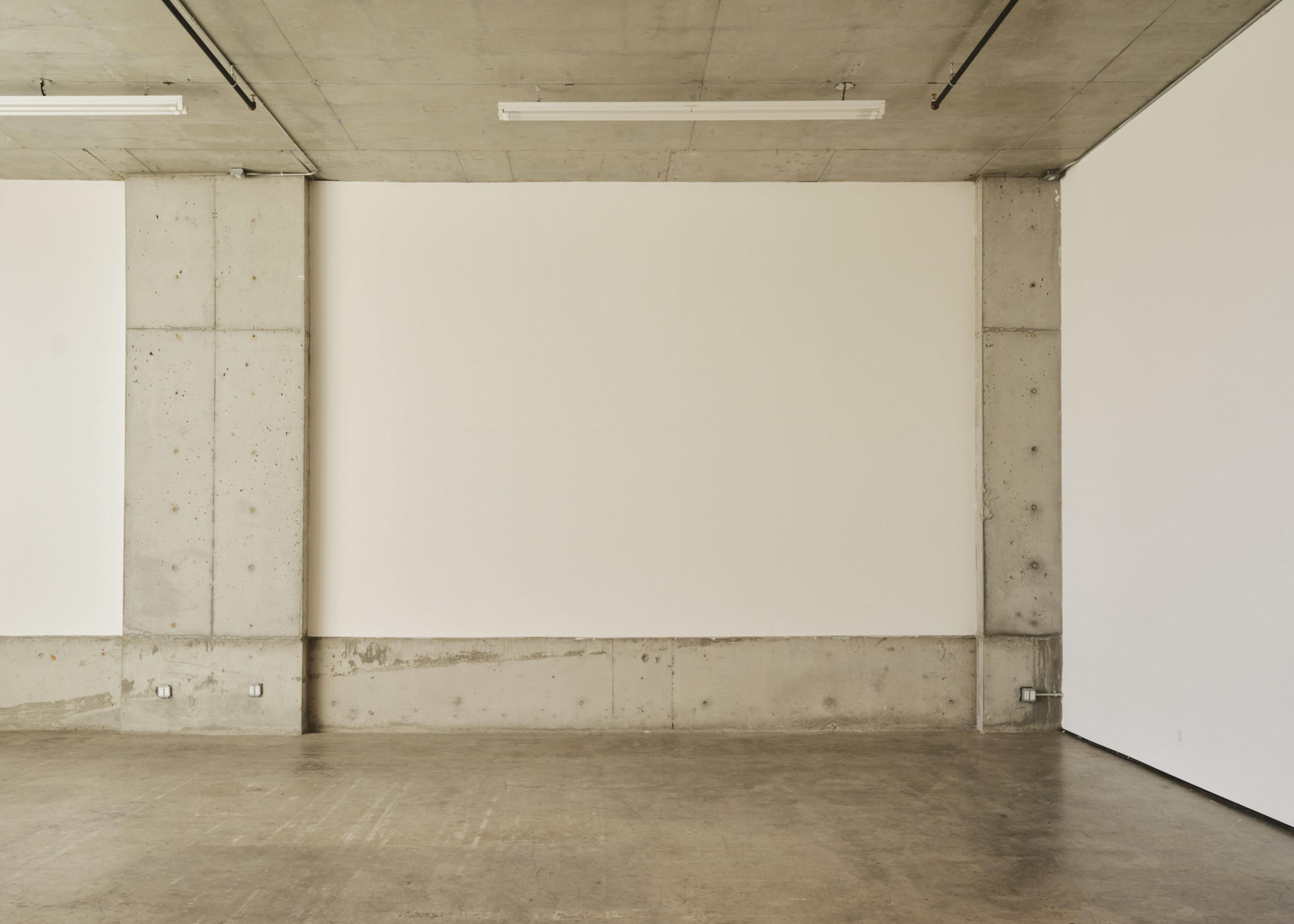 The image shows a blank, unobstructed interior space with concrete walls and a polished floor.