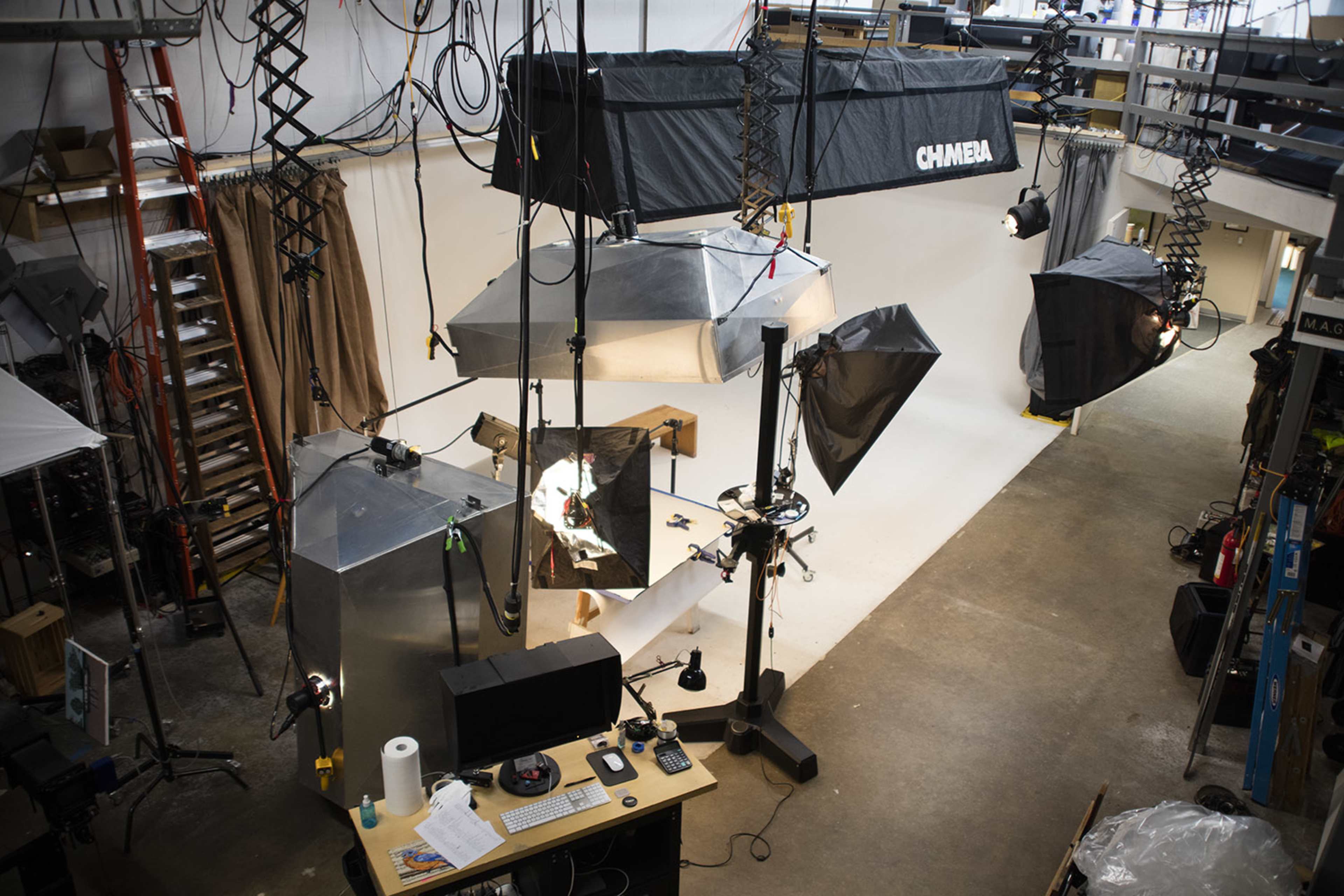 A photography studio equipped with multiple lighting setups, a computer workstation, and various backdrop materials.