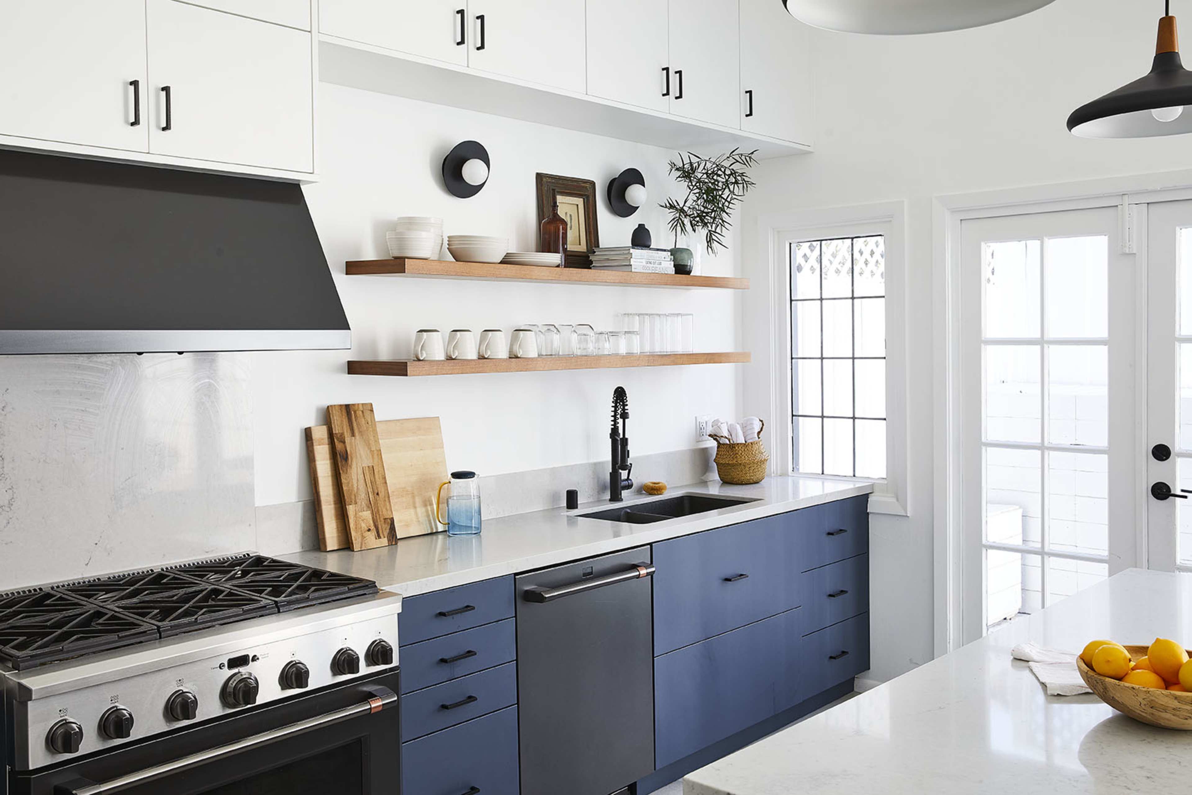 A modern kitchen features a stainless steel gas stove, a sleek black refrigerator, and open wooden shelves displaying dishware and decorative items.
