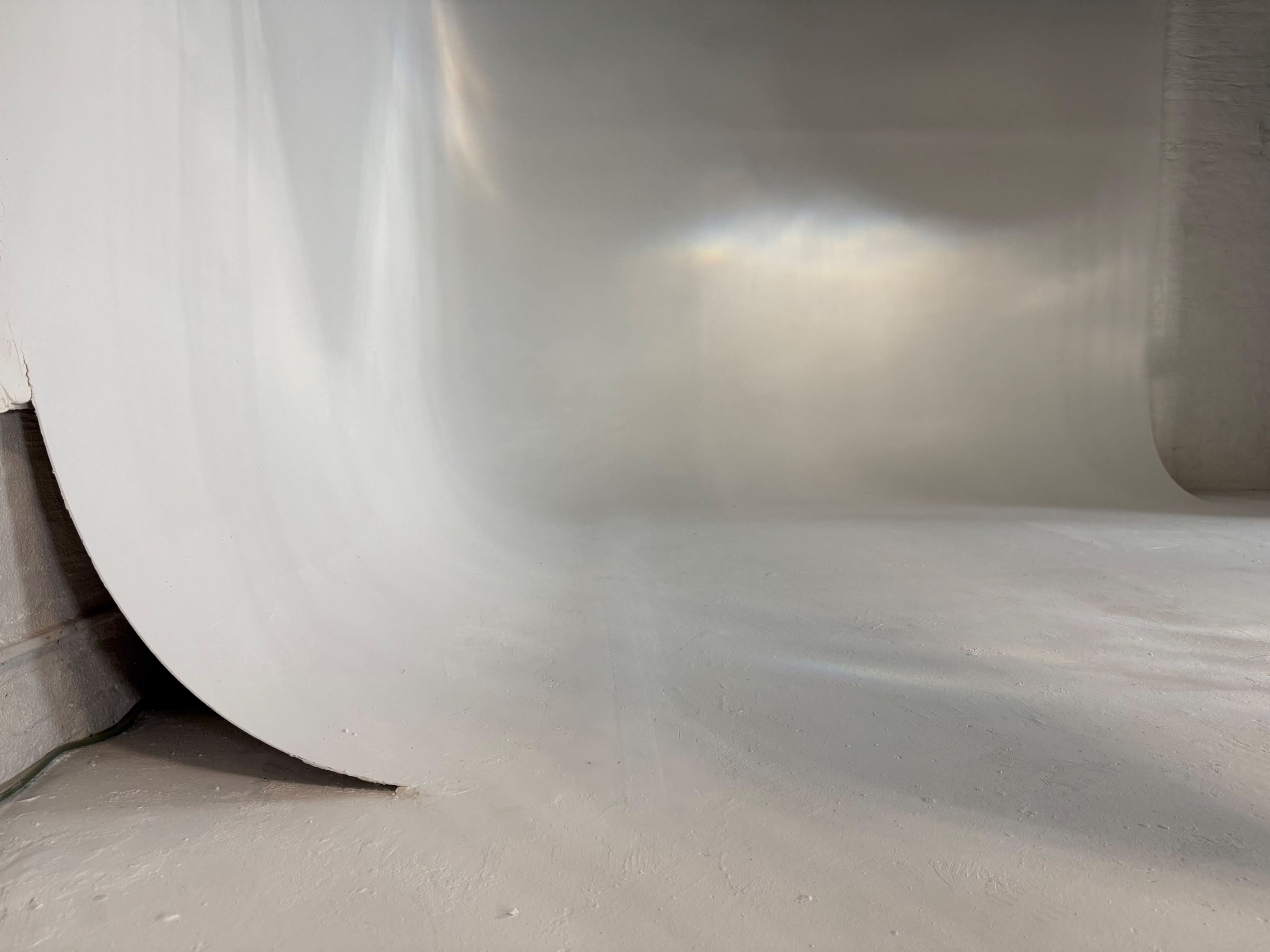 The image shows a smooth white backdrop that curves into a seamless transition from wall to floor in a photo studio setting.