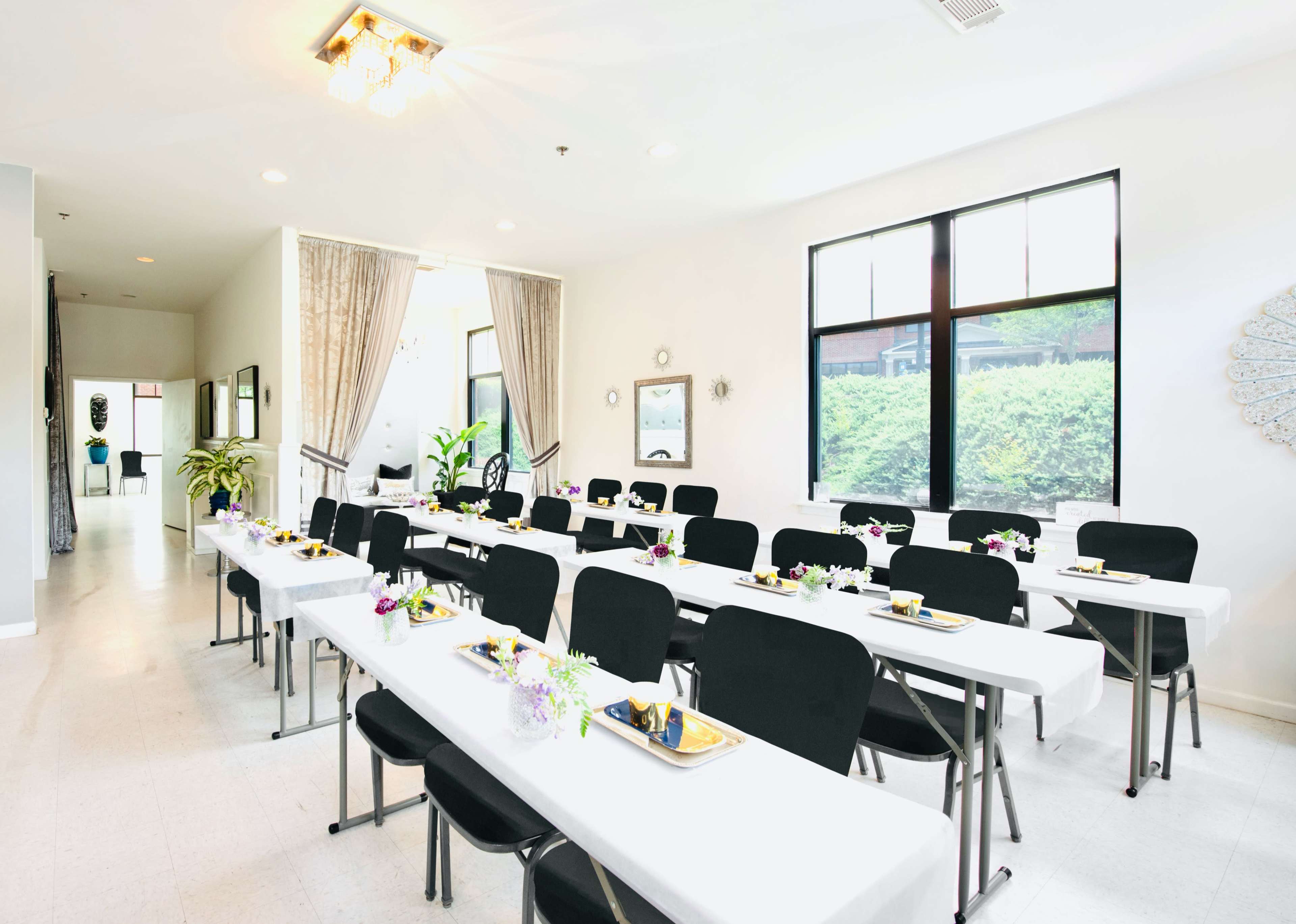 A well-organized indoor banquet room features several rows of tables set for a meal with black chairs and floral centerpieces.