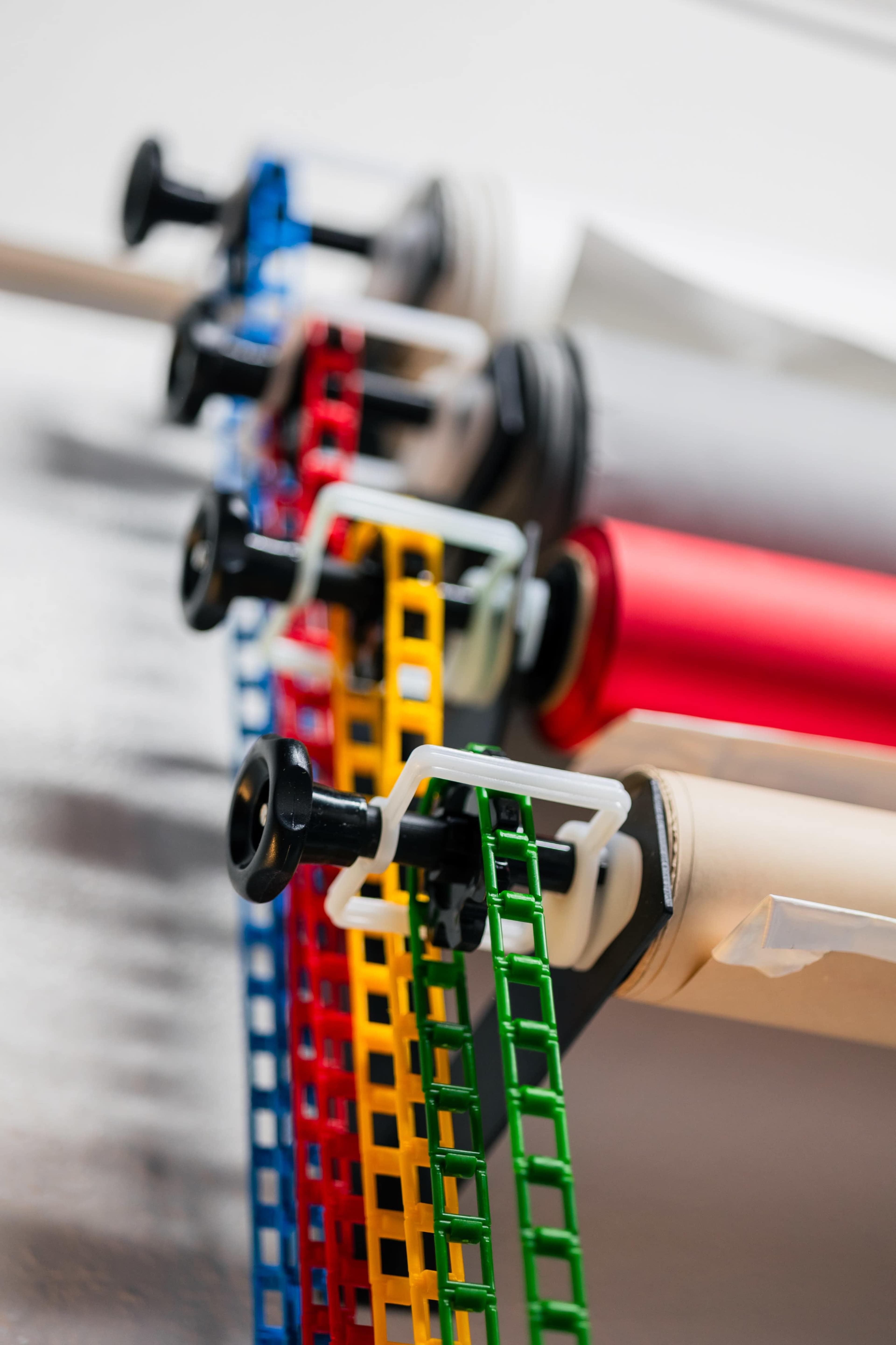 Several rolls of colored film or tape mounted on a wall, with mechanisms for dispensing each roll.