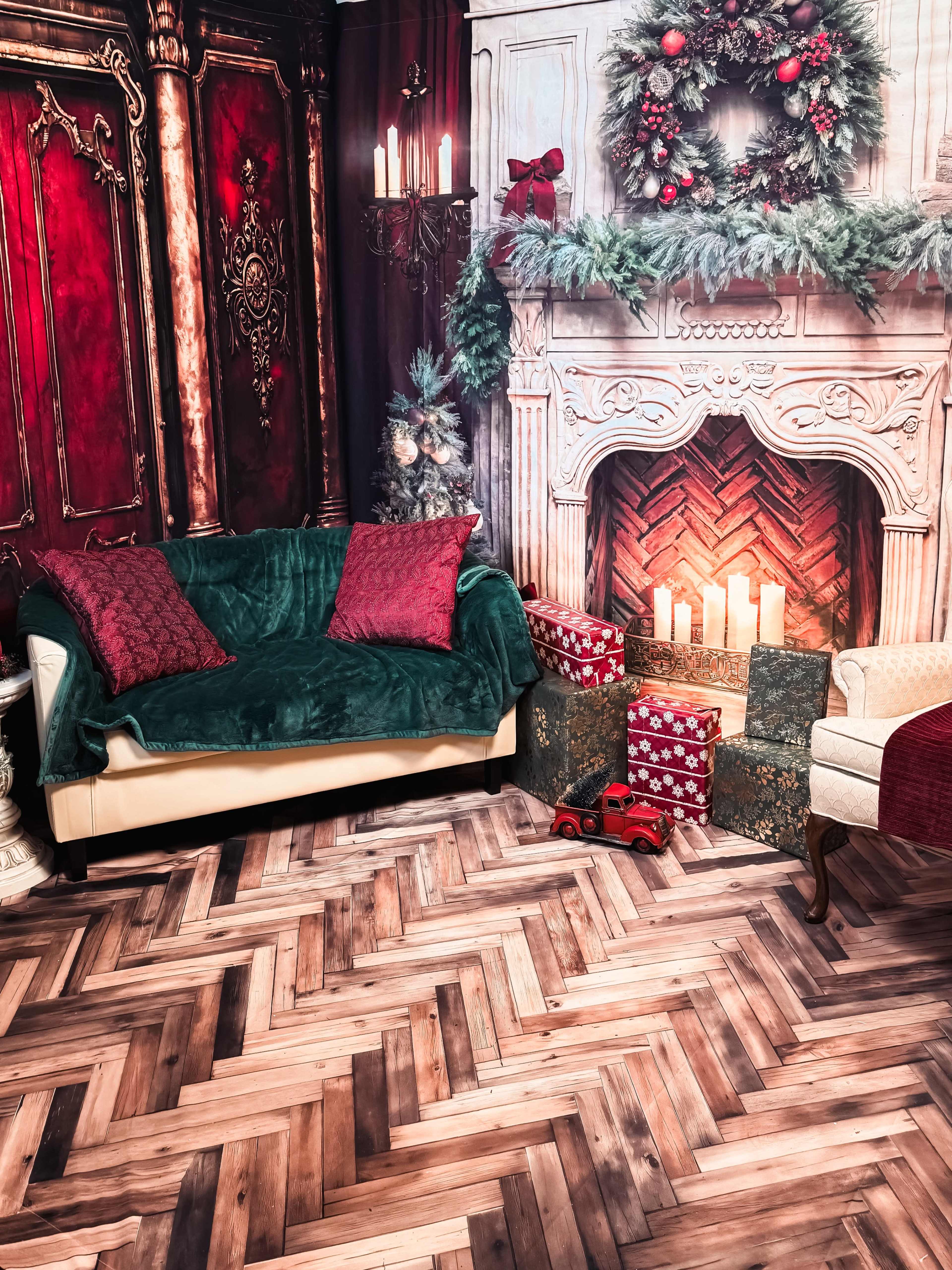 The scene features a cozy living room with a green and red-themed sofa, a decorative fireplace, and neatly arranged gift boxes under a festive mantle.