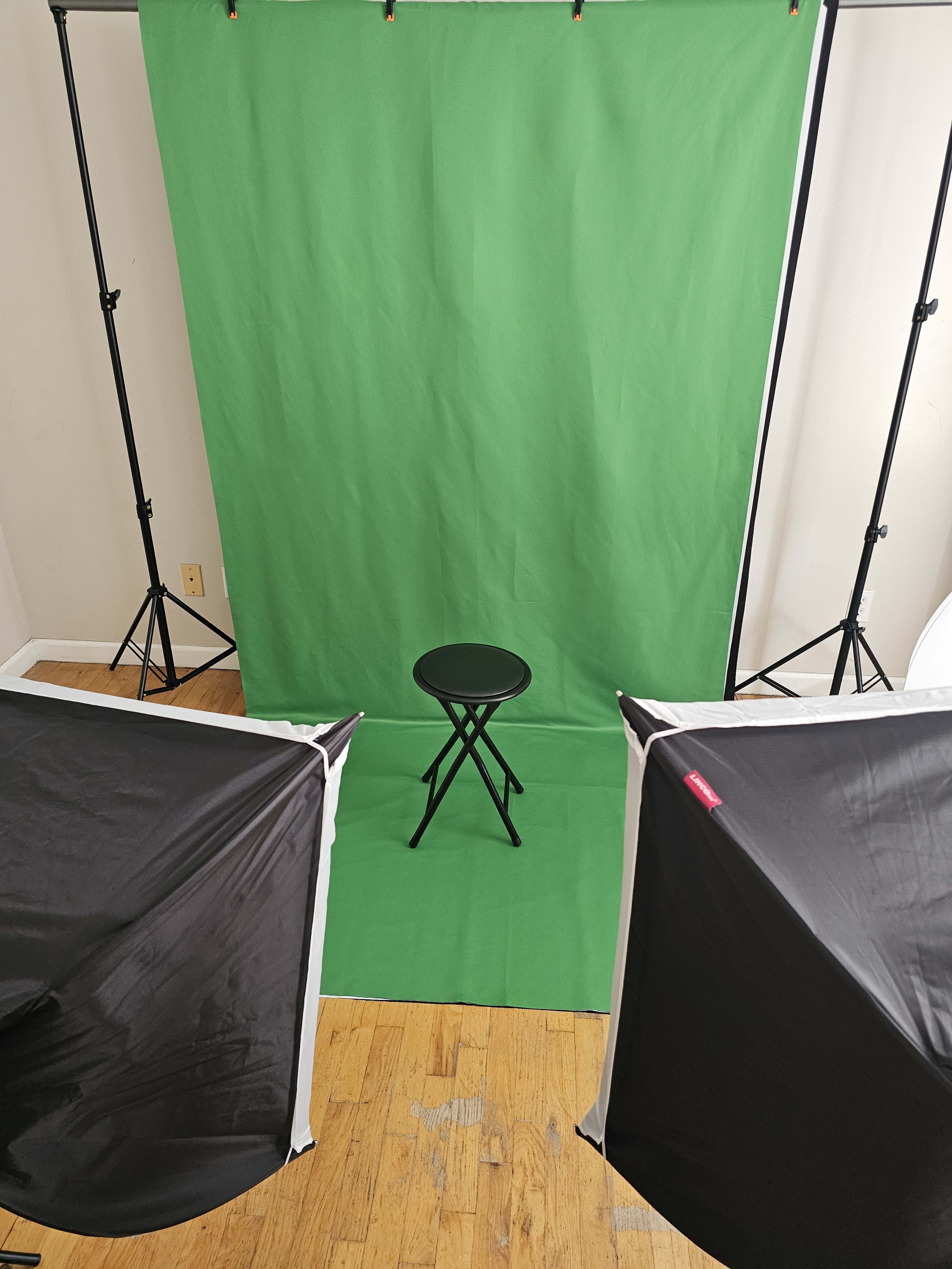 The image shows a photography setup featuring a black stool in front of a green backdrop, flanked by two softbox lights.