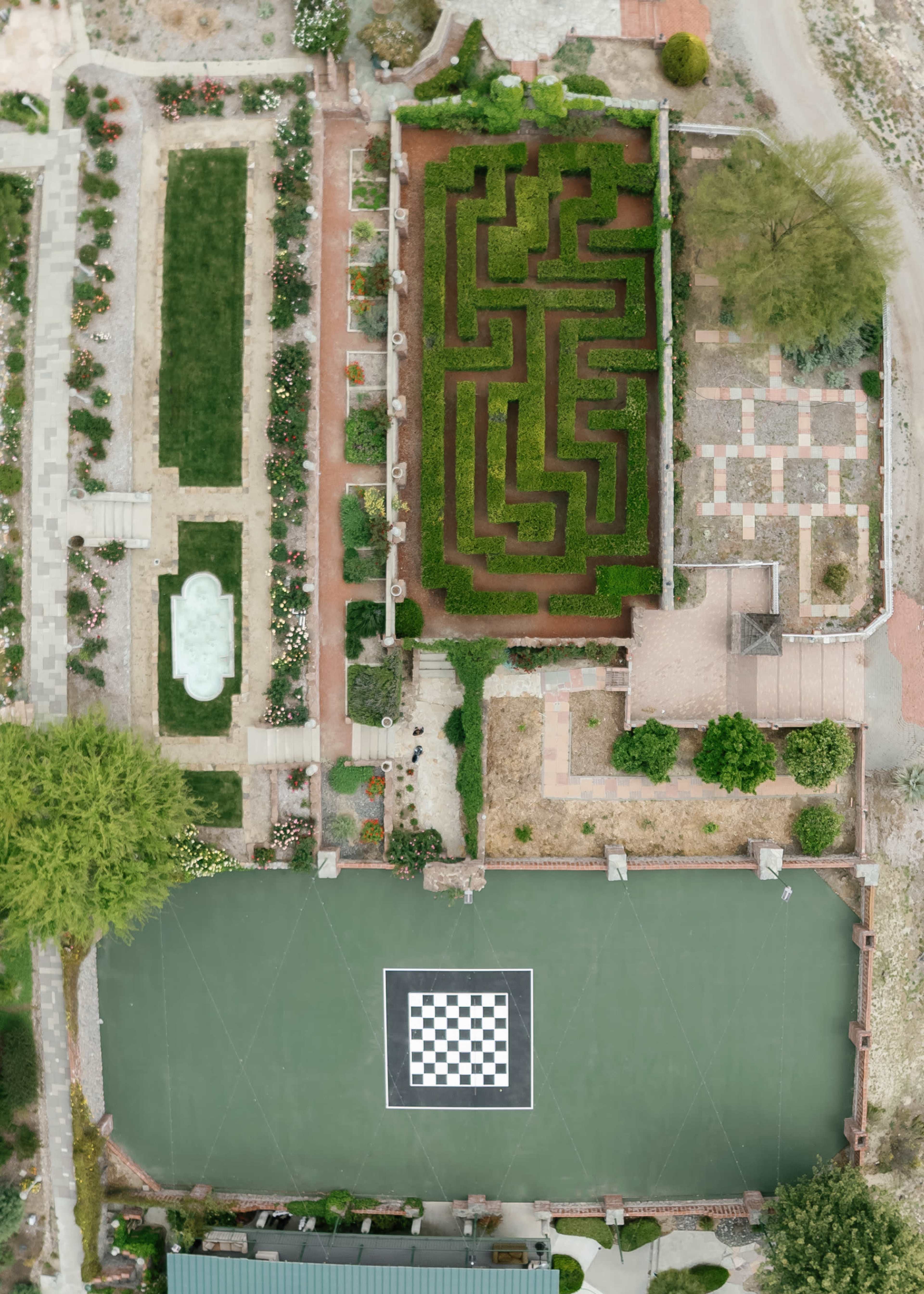 The image shows an aerial view of a garden featuring a maze, a checkerboard area, and landscaped sections with pathways.
