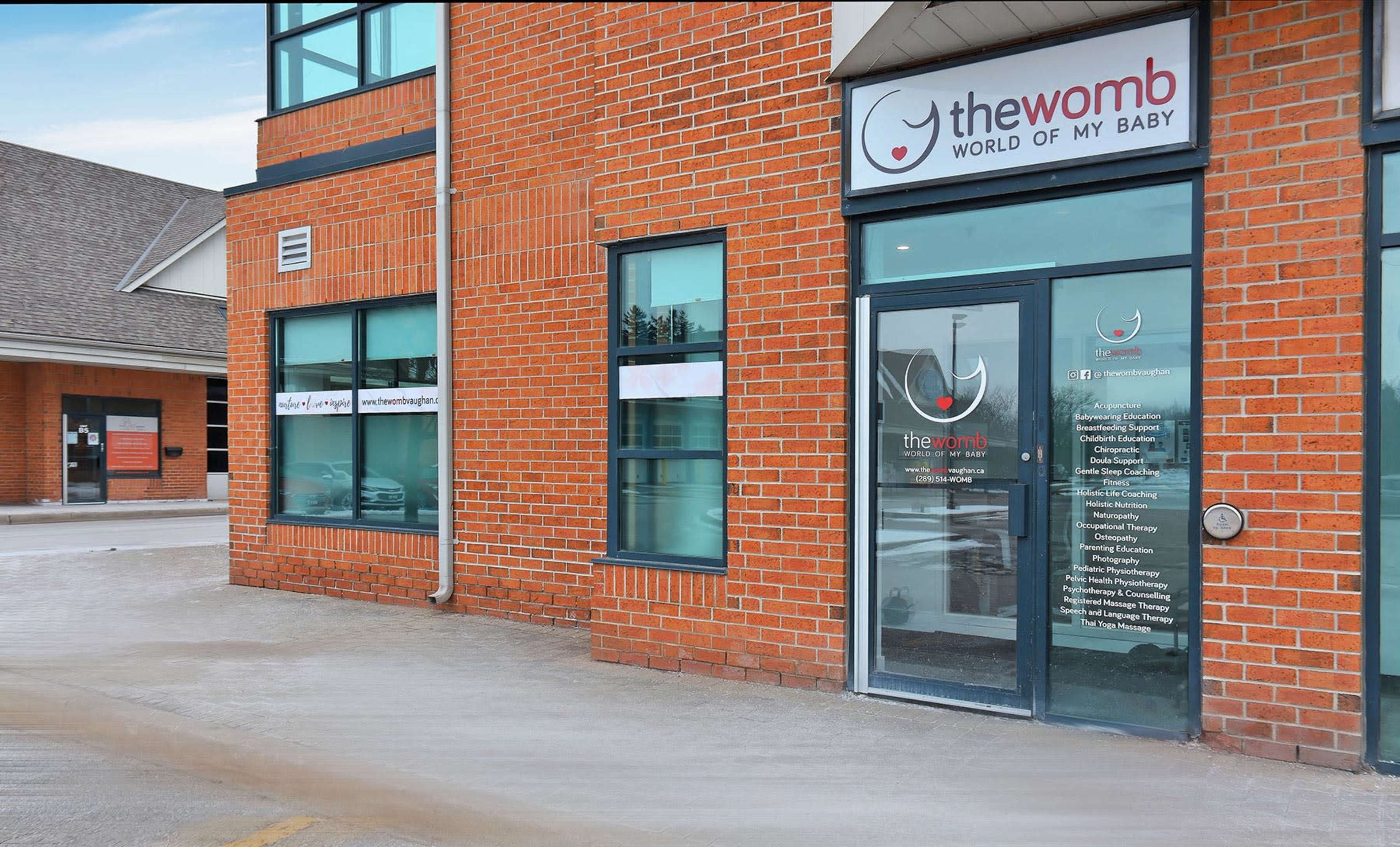 The entrance to a brick building labeled "the womb" with large glass doors and windows.